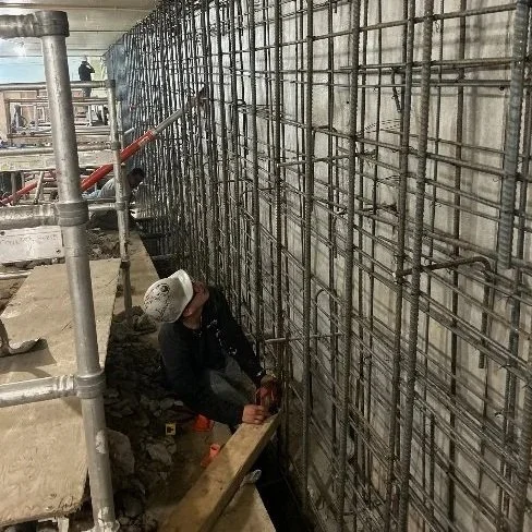 Construction worker installing rebar in a concrete wall.