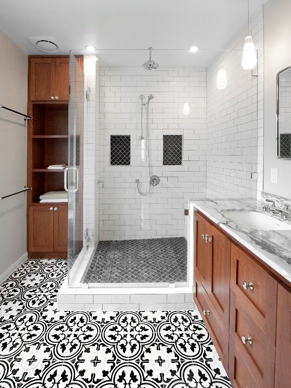 Bathroom with a walk-in shower, black and white patterned tile floor, wooden cabinets, white subway tile walls, and a marble vanity top.