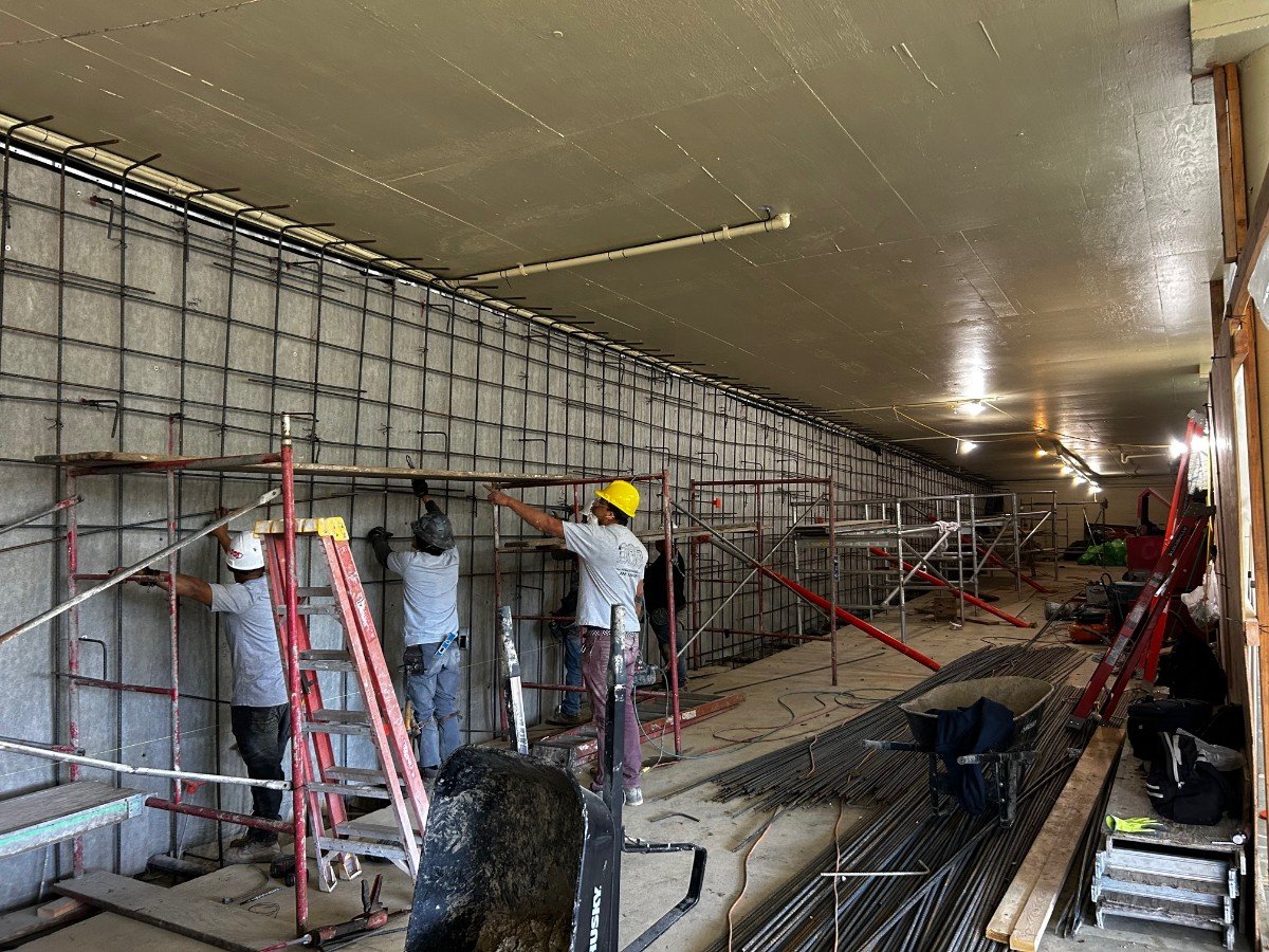 Construction workers in hard hats working on scaffolding inside a building.