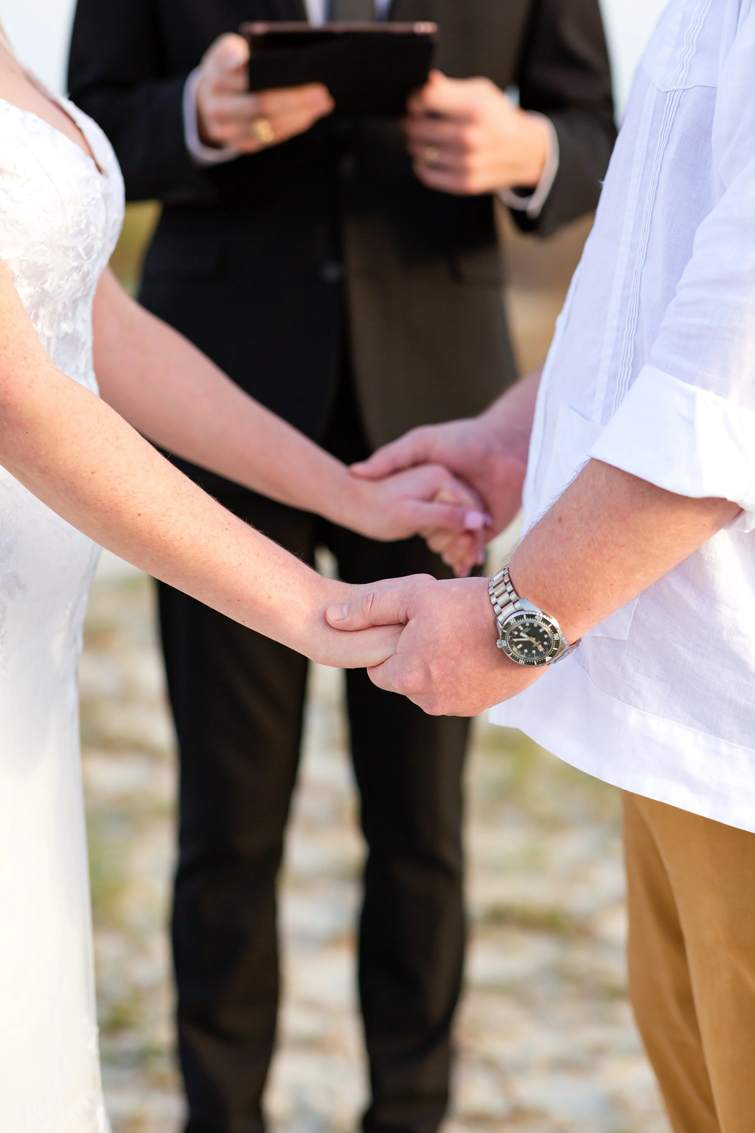 Couple holding hands during beach wedding ceremony