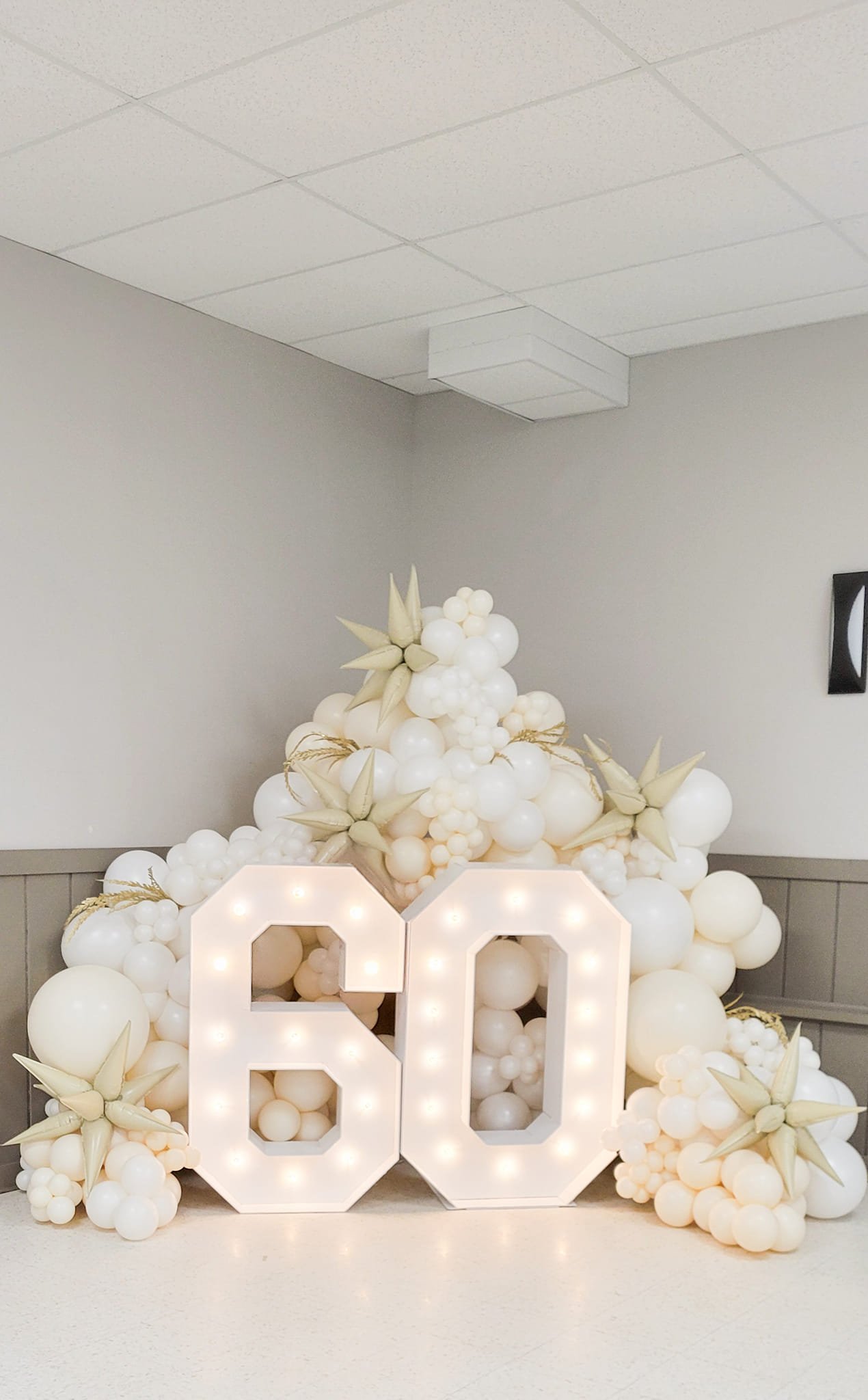 Decorative display with white balloons, star-shaped accents, illuminated number '20', set up for a celebration or event.