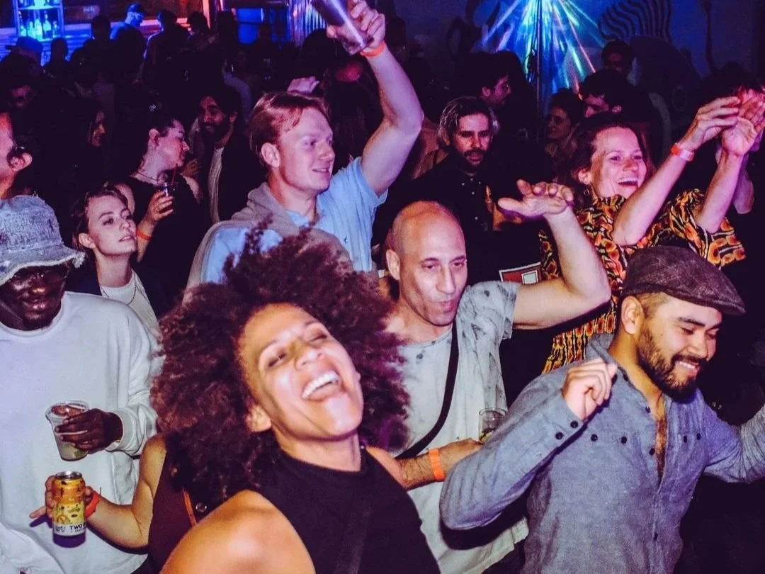 People dancing and enjoying themselves at a lively party or nightclub, with colorful lighting and happy expressions.