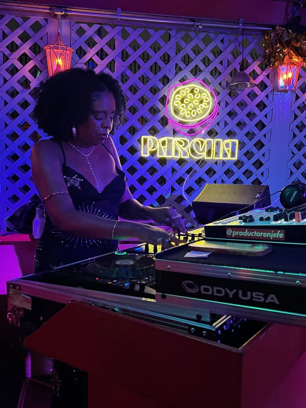 DJ playing at a Parcha Presents show, neon PARCHA sign behind