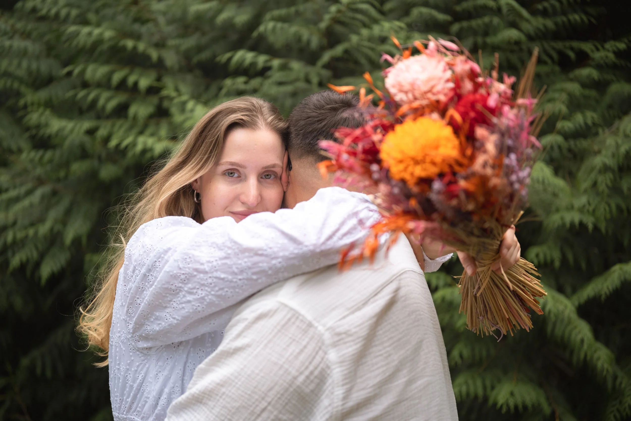 Ein umarmendes Paar und die Frau hat getrocknete Blumen in der Hand