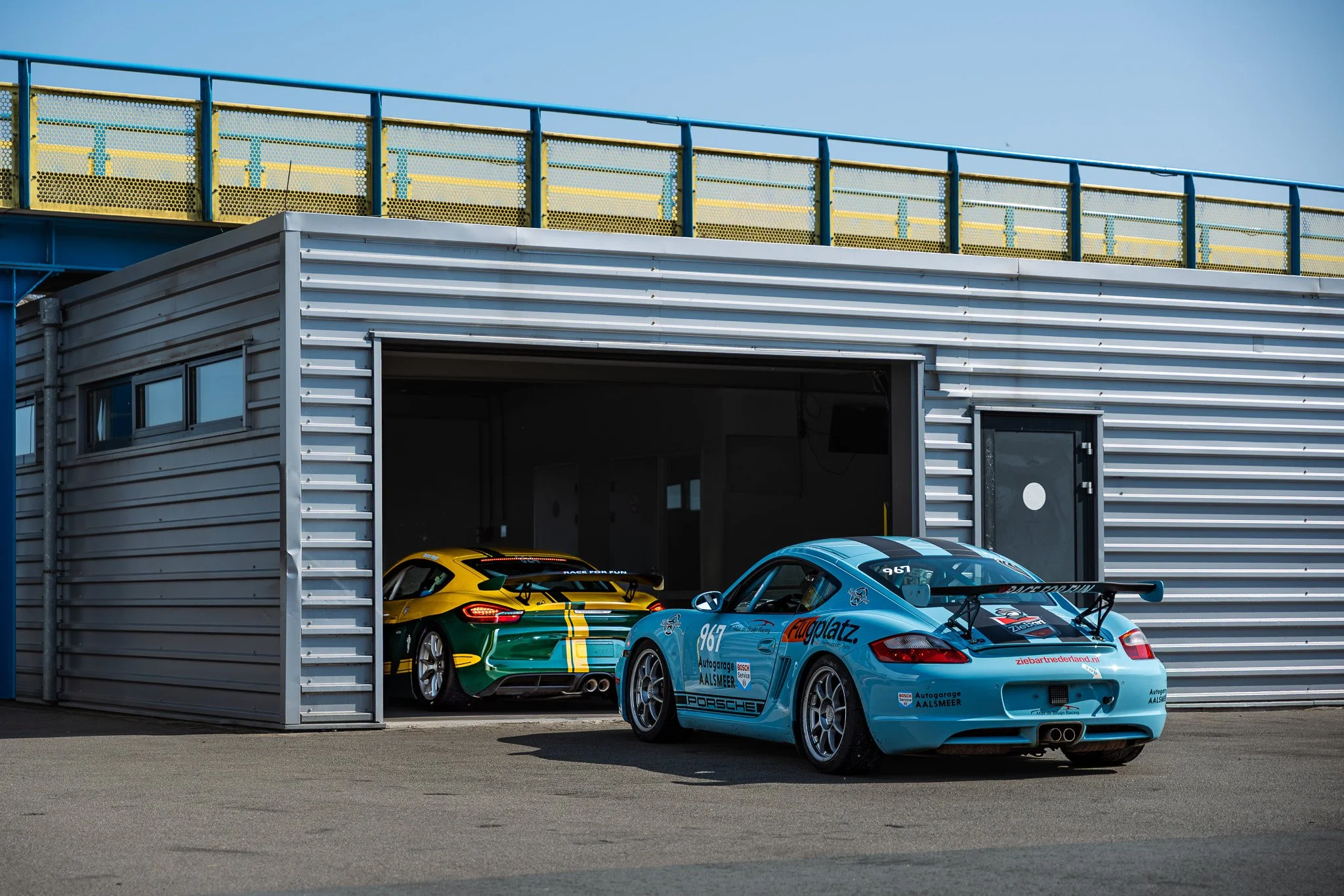 Twee raceauto's statues onder een metalen gebouw in de buitenlucht.