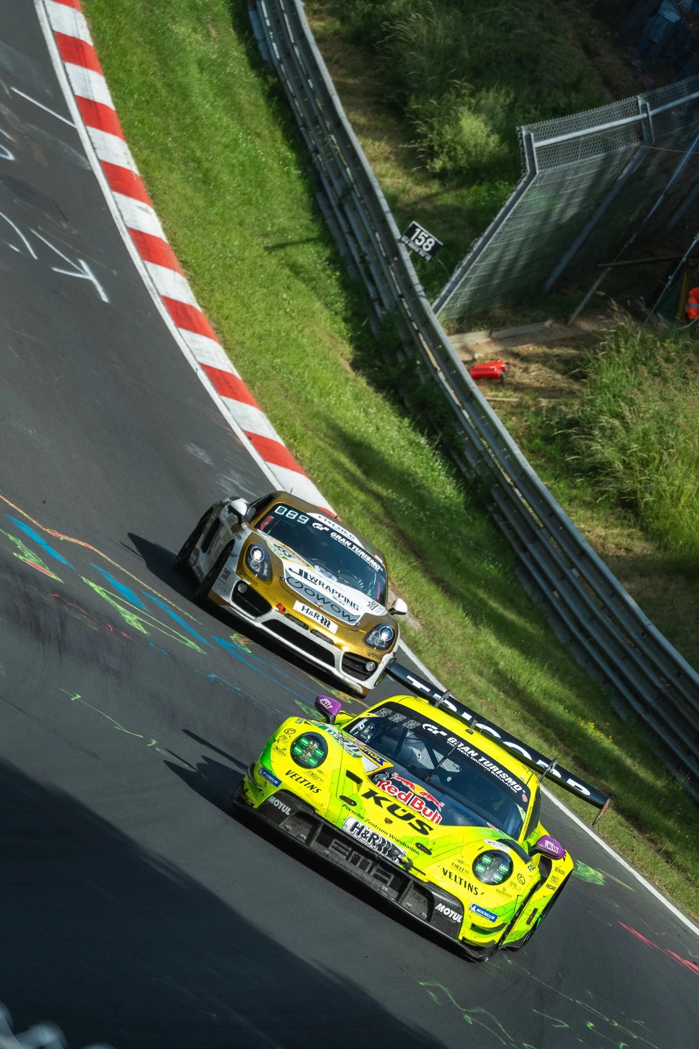 Raceauto op een circuit met meerdere raceauto's en een groene omgeving.