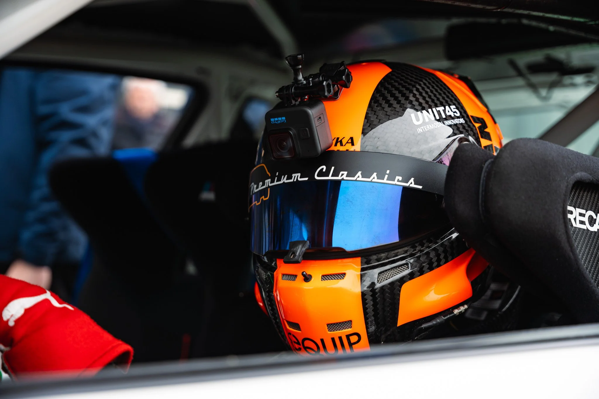 Racing helmet inside a race car, with a GoPro camera mounted on top.