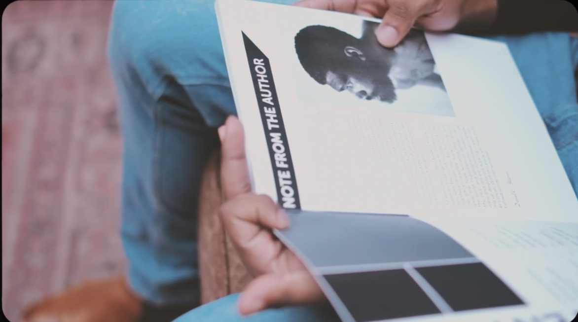 Person holding an open book showing a note from the author.