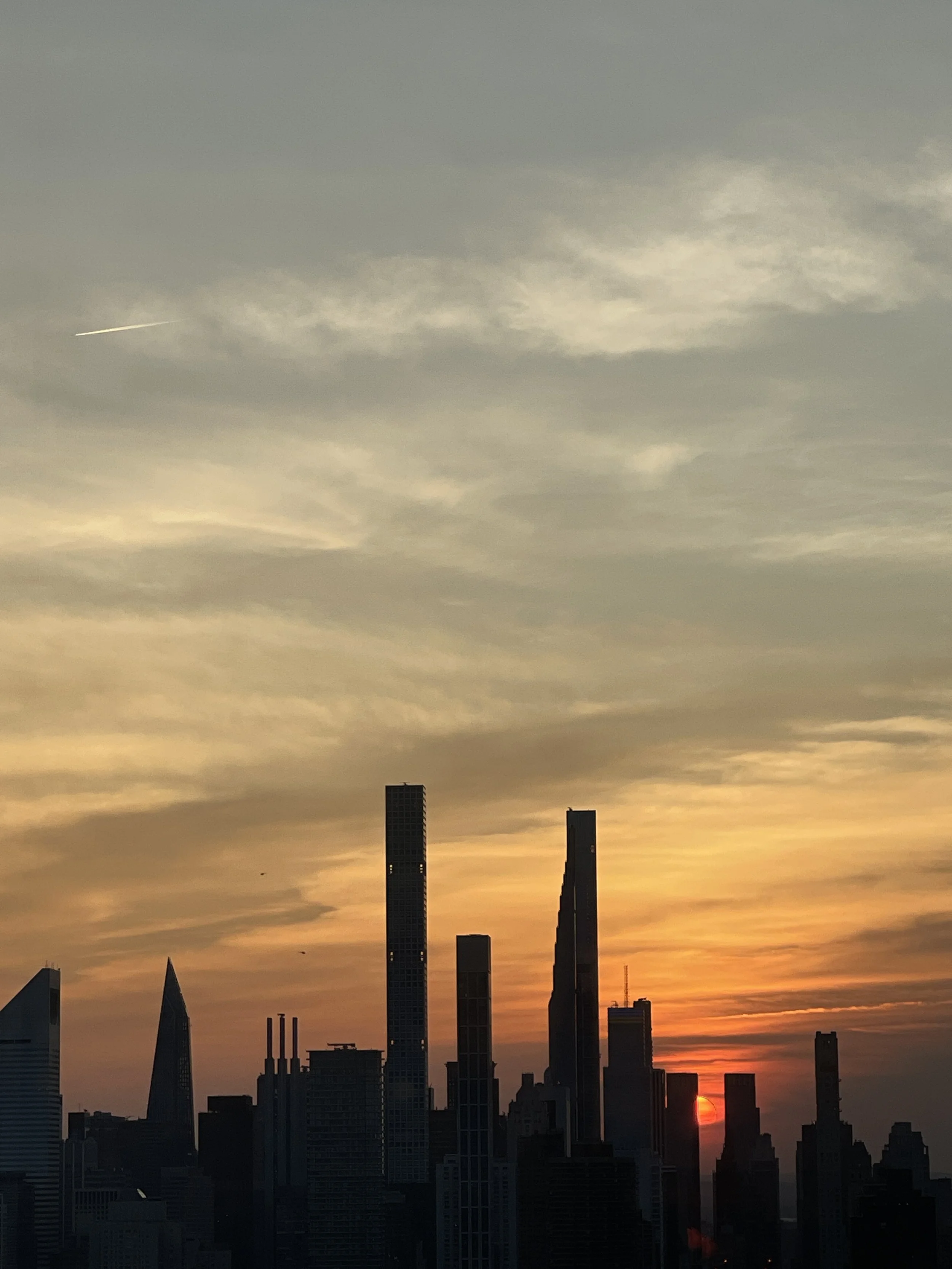 New York City skyline silhouetted against a soft sunset sky.