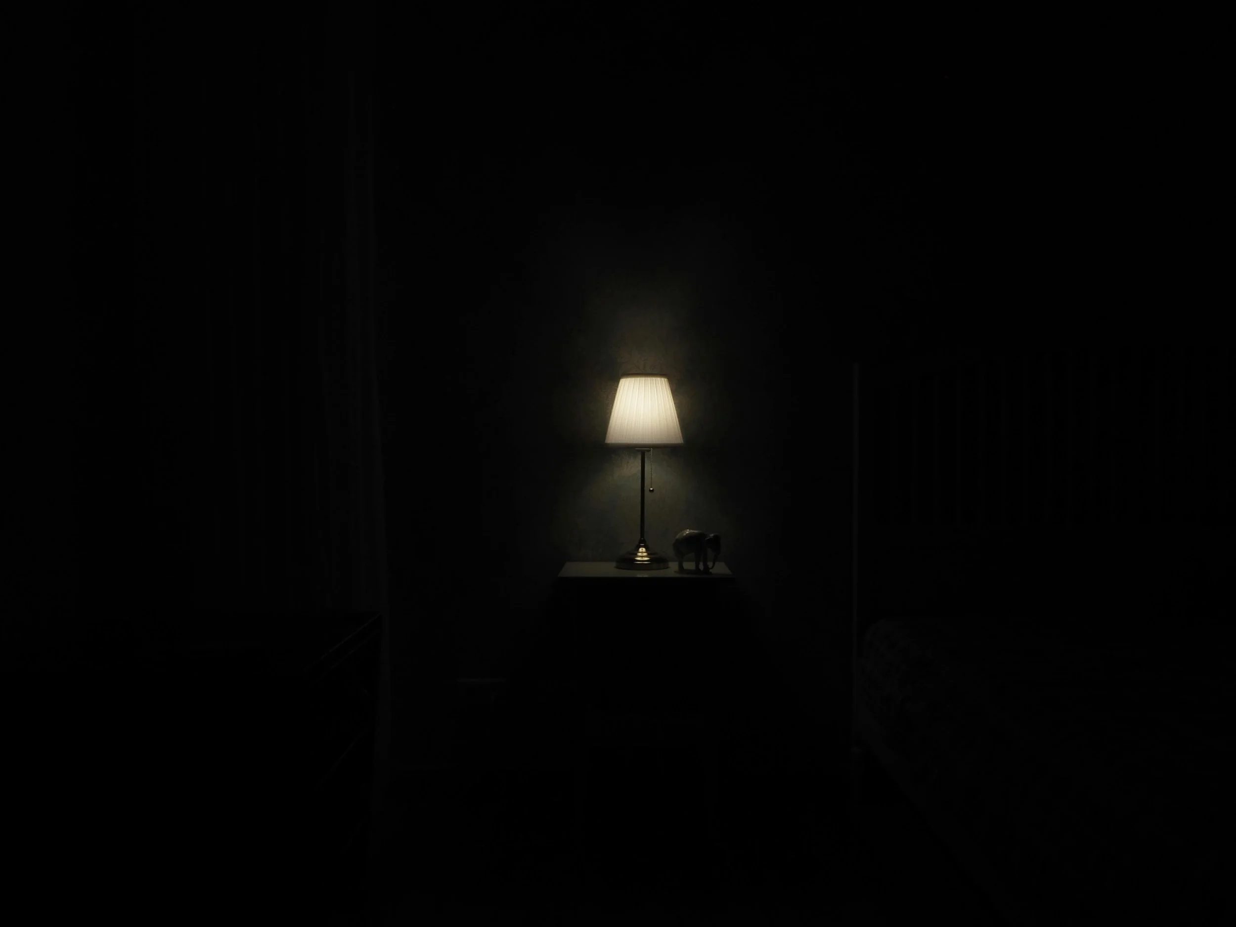 A single lamp glowing in a dark room, symbolizing protected inner work and quiet faith.