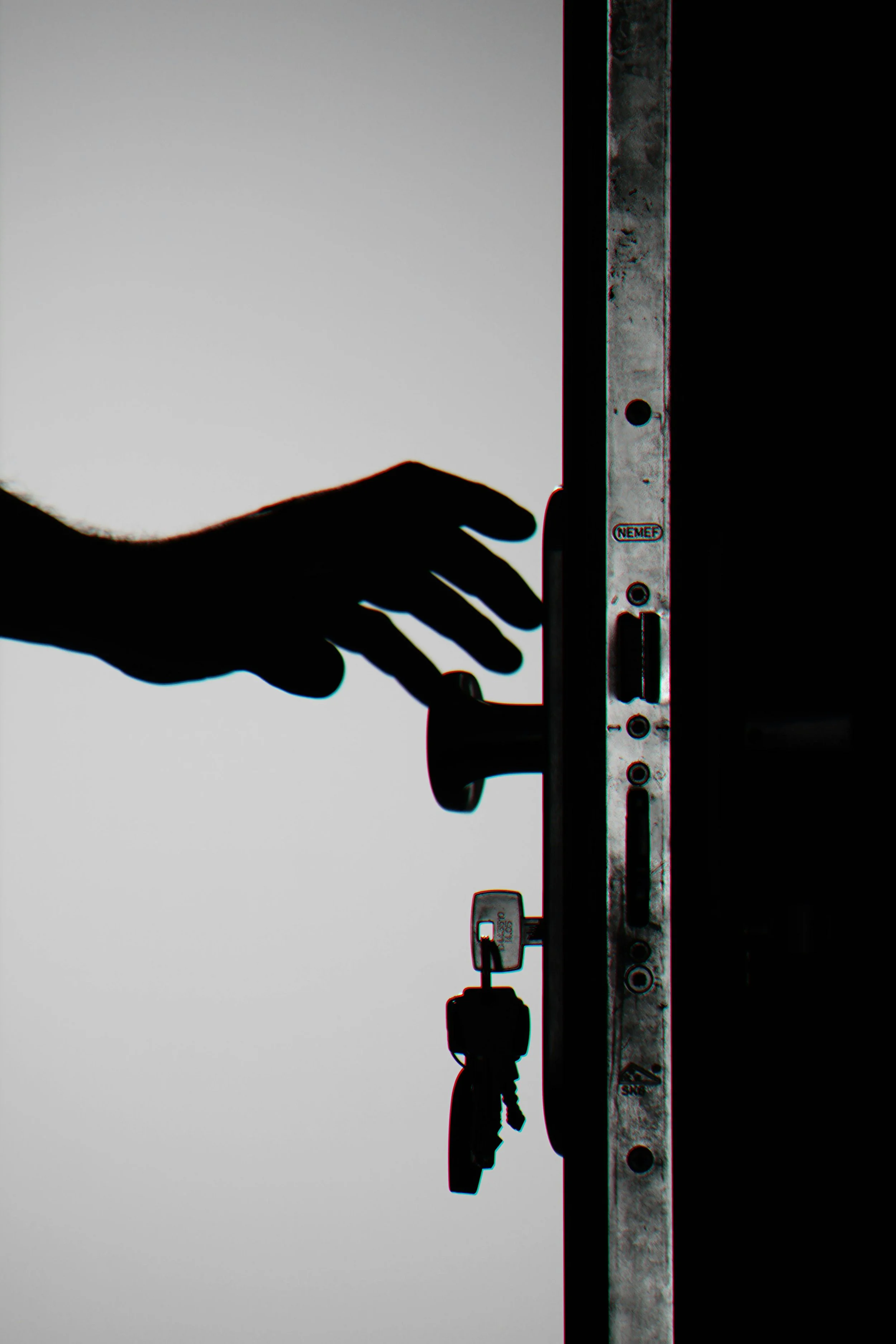 Silhouette of a hand reaching for a door handle with keys.