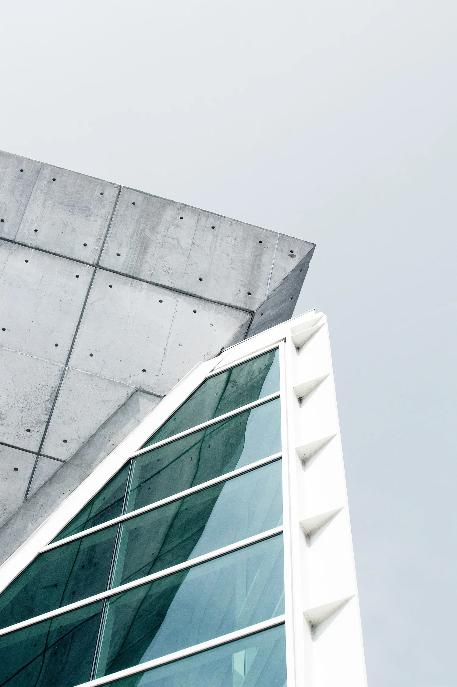 Modern building with glass panels and concrete wall against cloudy sky
