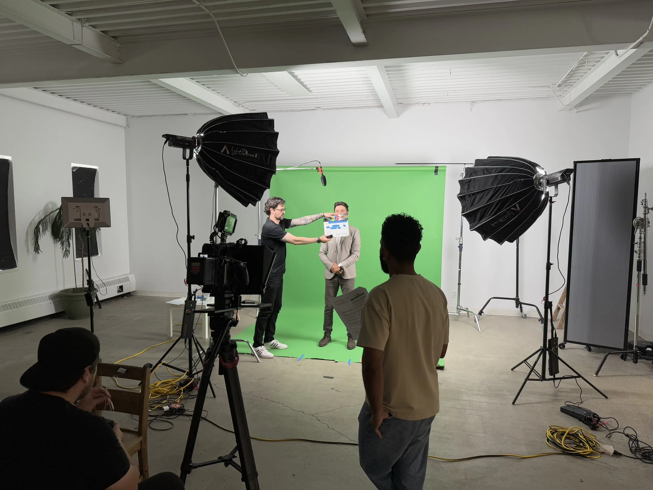 Behind-the-scenes of a video shoot showing a green screen, studio lights, and crew members preparing for filming.