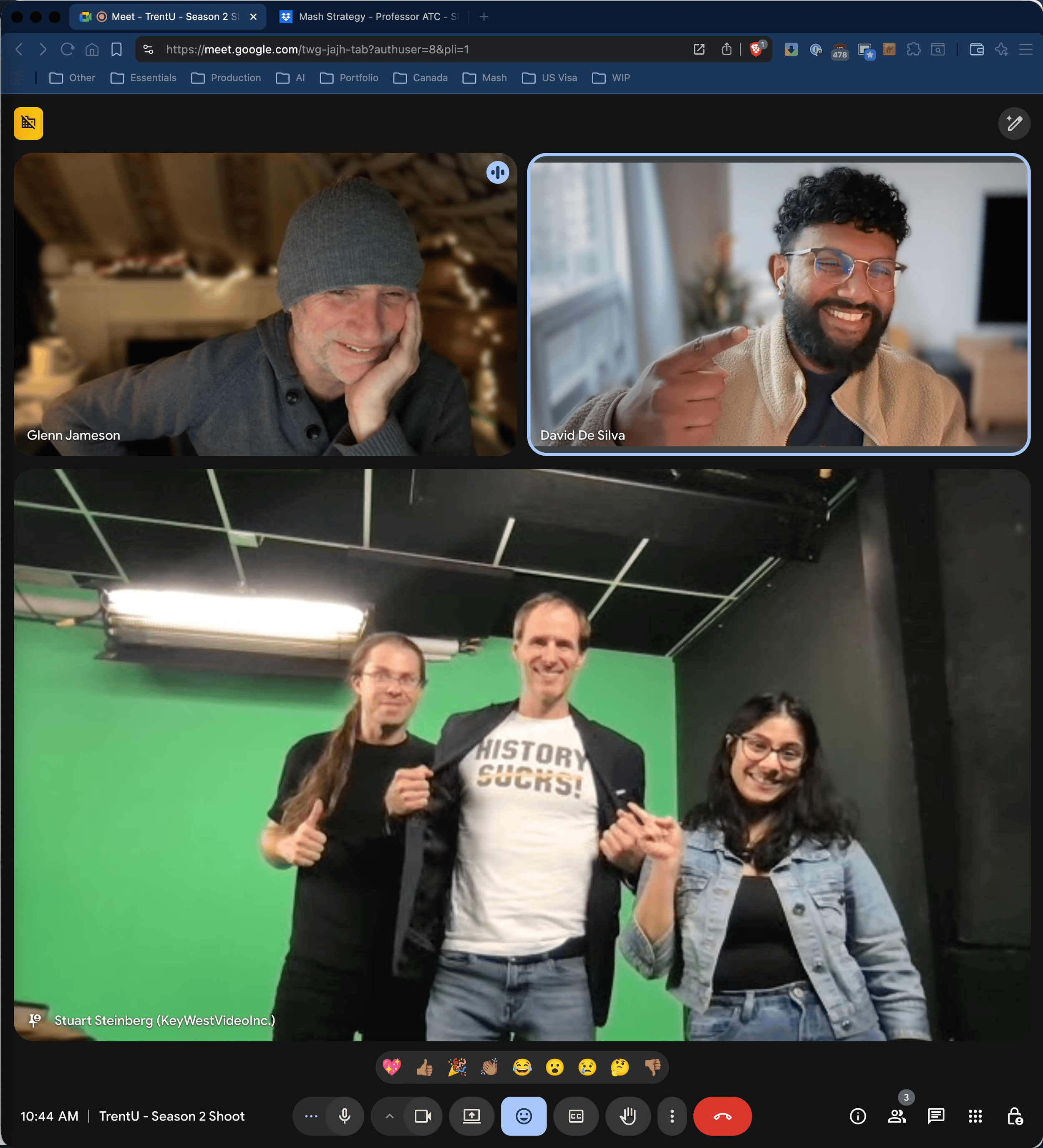A group of five people standing in front of a green screen, smiling and posing for a photo during a video call, with some making gestures like thumbs up and pointing.