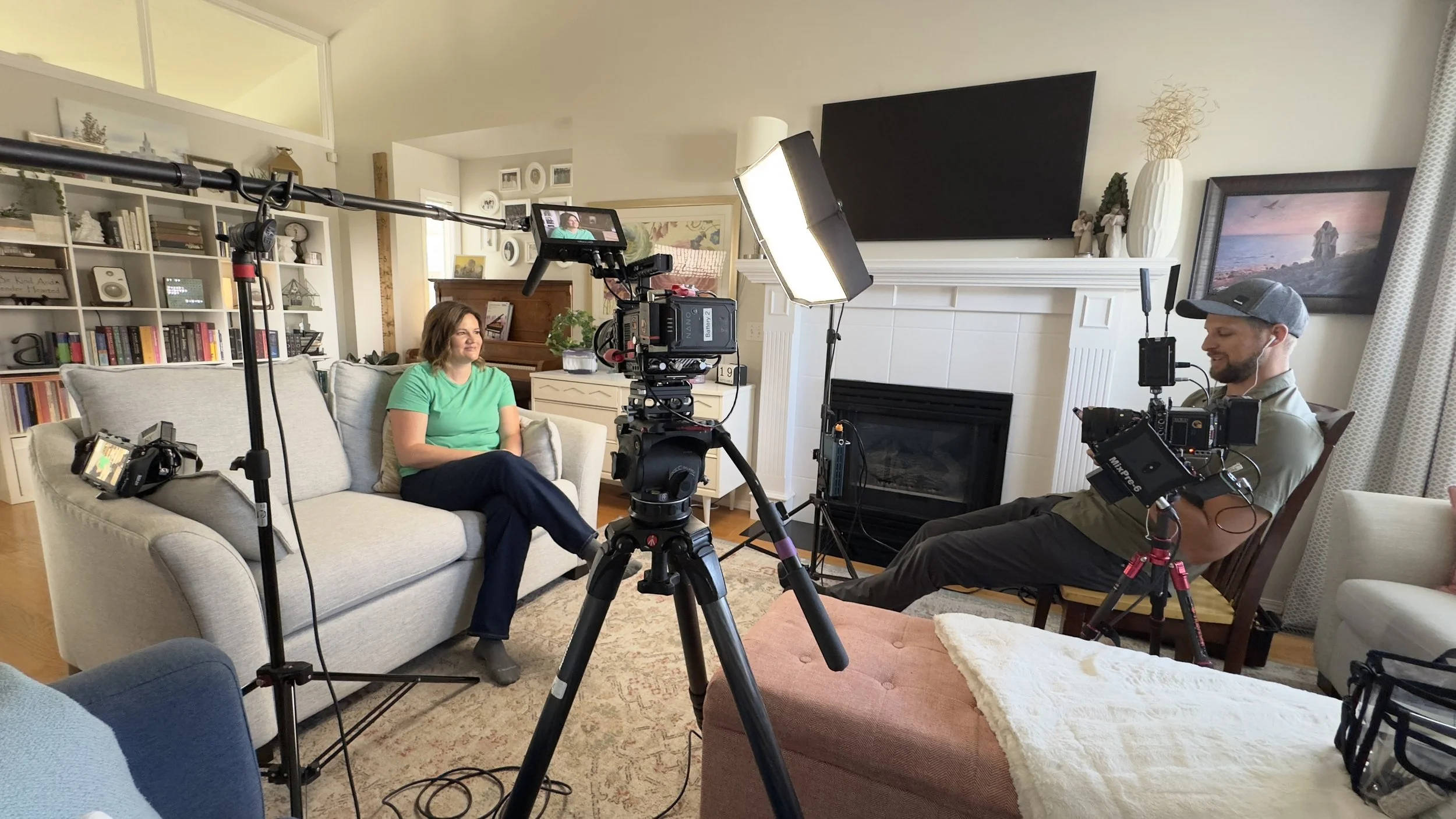 A woman being interviewed in a cozy living room with cameras and lighting equipment.