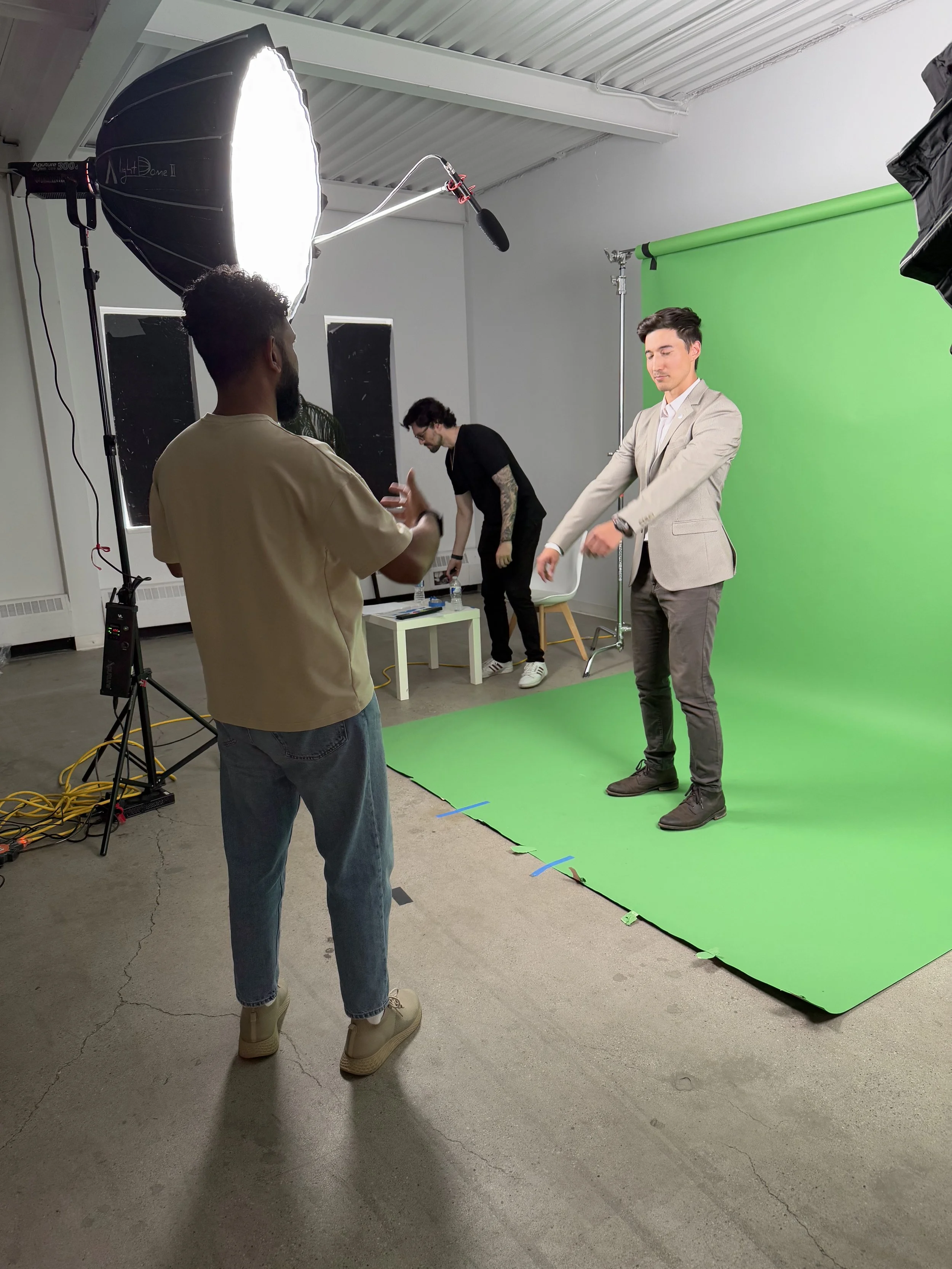People working on a green screen for a video or photo shoot in a studio with professional lighting and equipment.