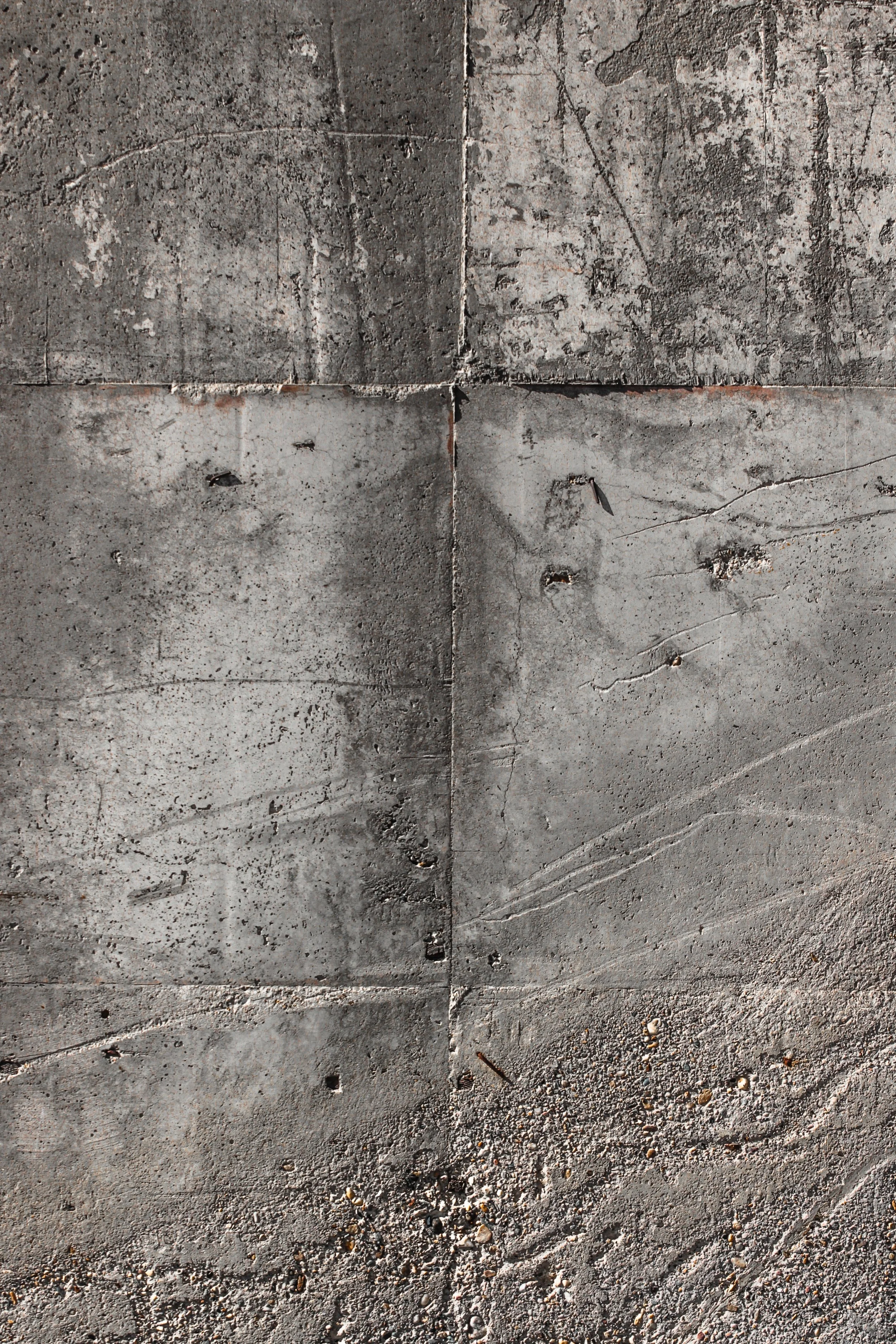 Close-up of a worn, gray concrete sidewalk with cracks, small holes, and scattered debris.