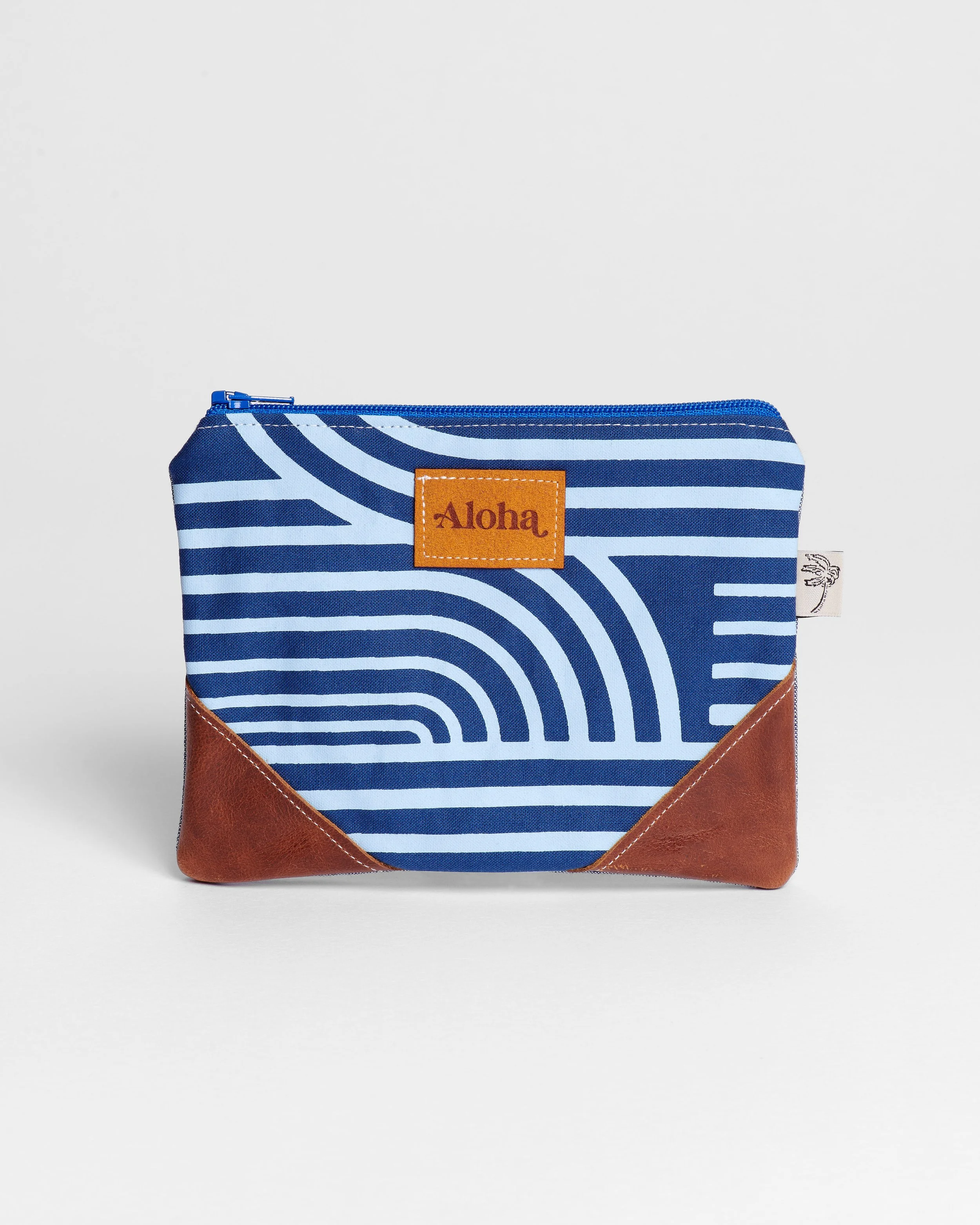 Blue and white striped fabric pouch with brown leather accents and a label that says "Aloha."