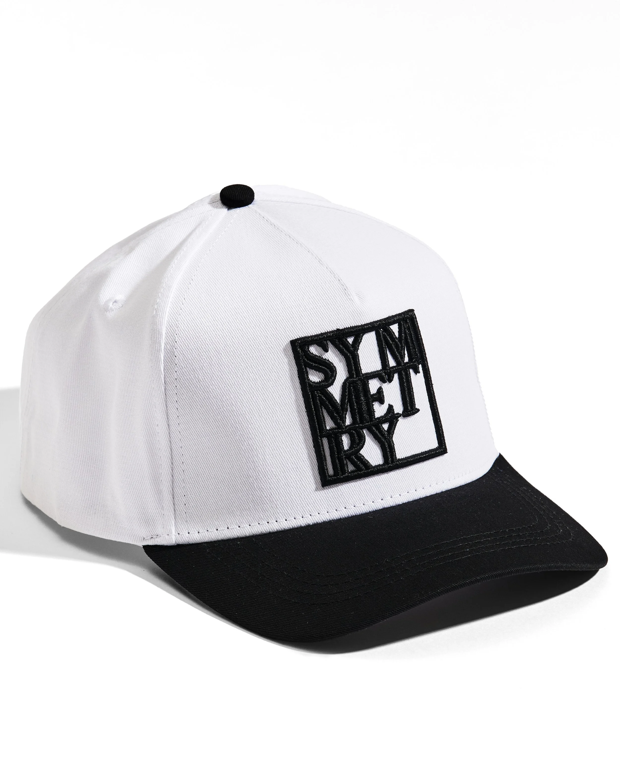 White and black baseball cap with a black embroidered square patch on the front.