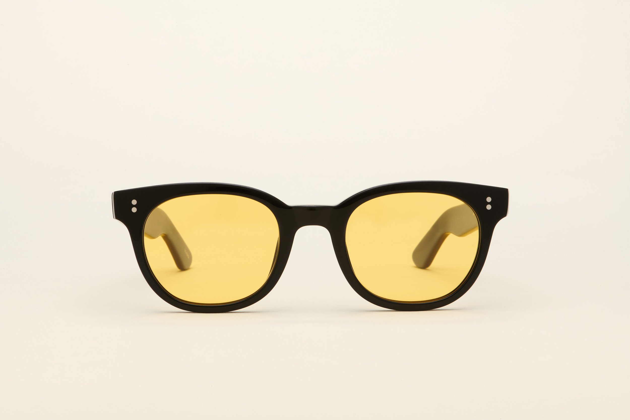 Black sunglasses with yellow tinted lenses on a plain white background.