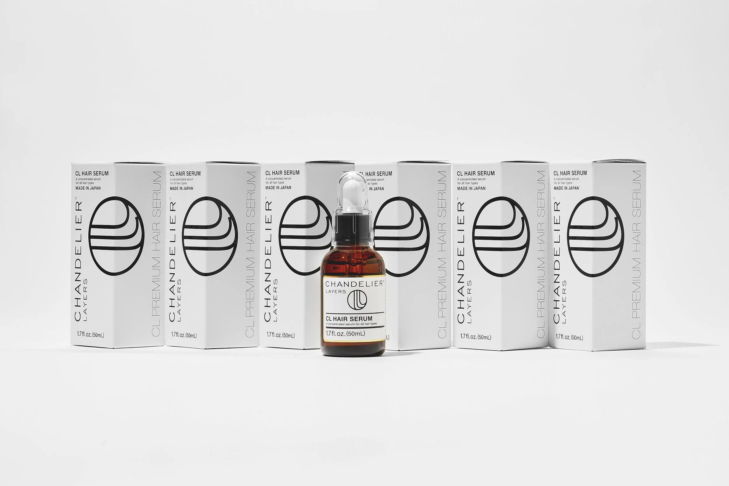 Bottle of Chandler Layers CL Hair Serum in front of multiple white boxes with black logo and text.