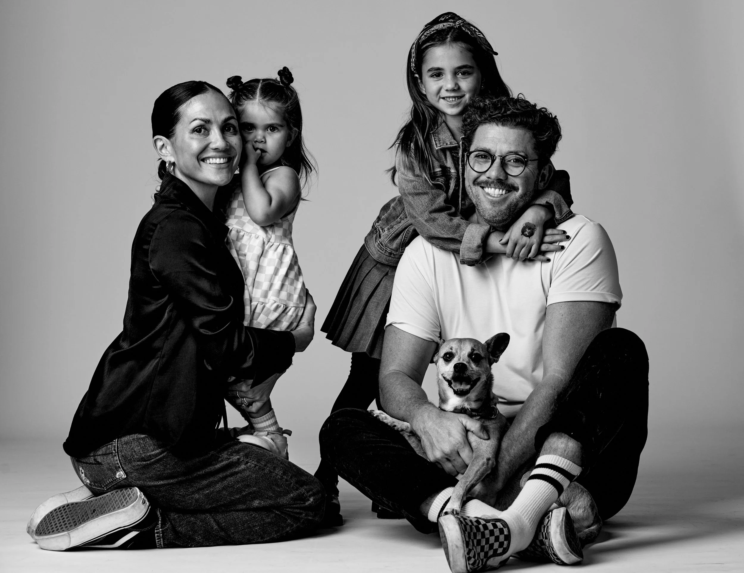 A black-and-white photo of a family portrait of four with a dog