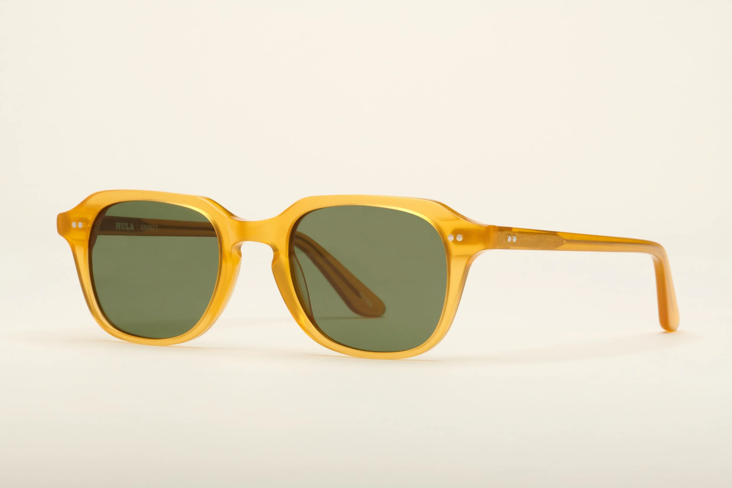 Yellow sunglasses with dark green lenses on a white background.