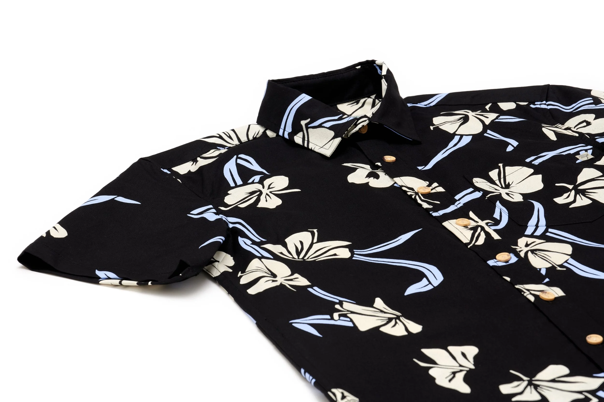Close-up of a black Hawaiian shirt with a floral print of cream and light blue flowers and blue stripes, laid flat on a white background.