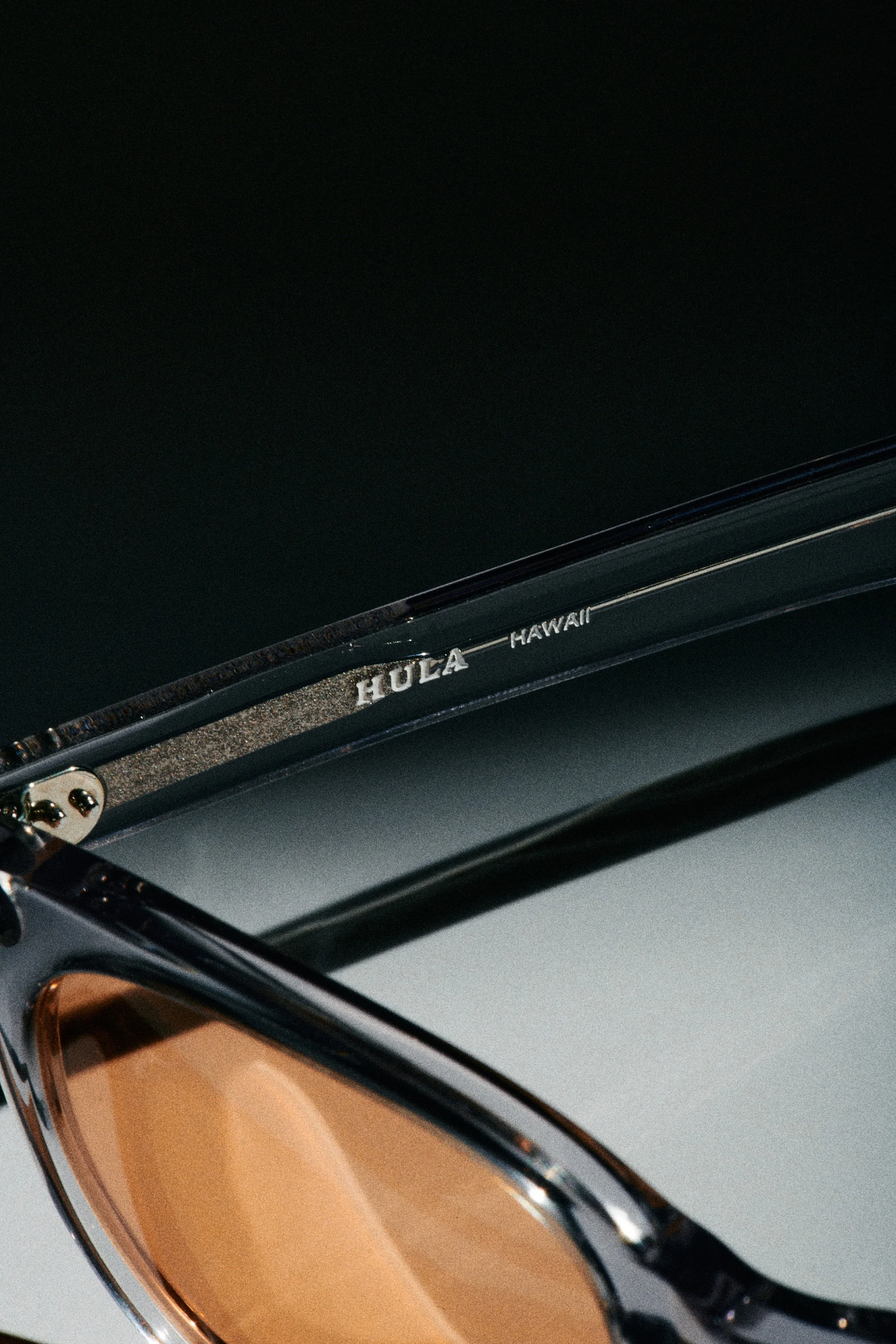 Close-up of a sunglasses with the brand name 'HUEA' and the word 'HAWAII' visible on the inside arm.