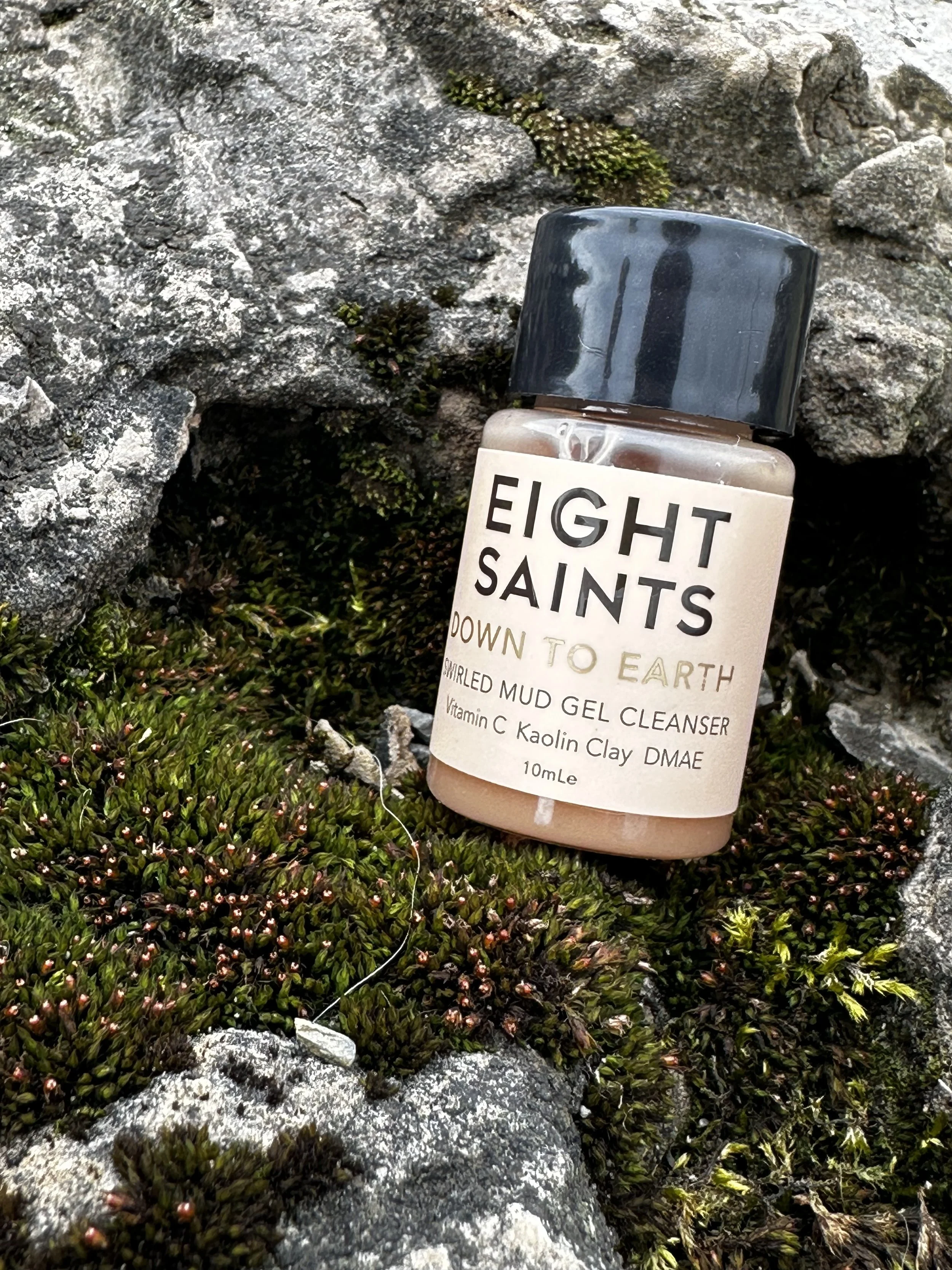 Bottle of Eight Saints Down to Earth whipped mud gel cleanser among rocks and moss.