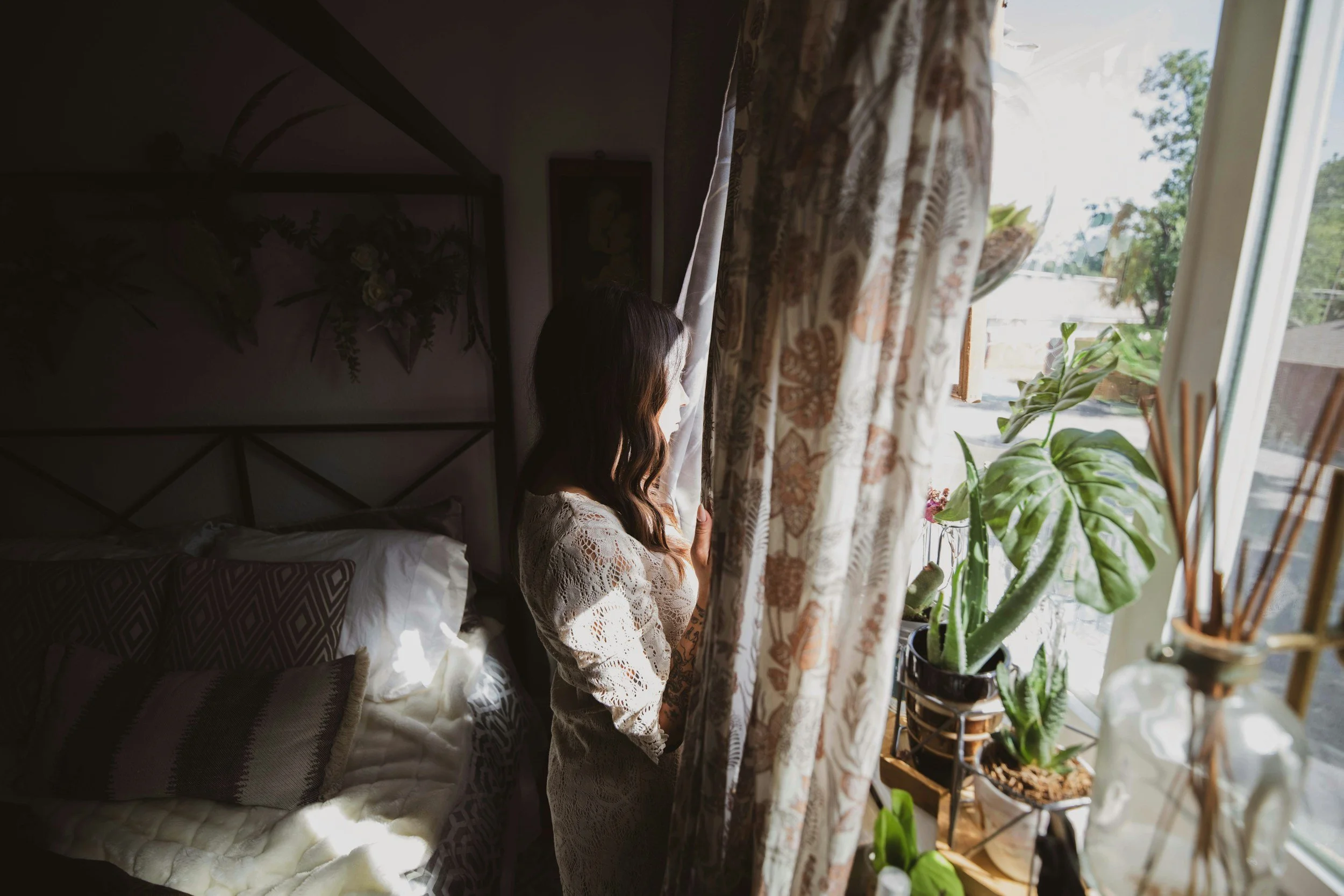 woman looking out window with curtains