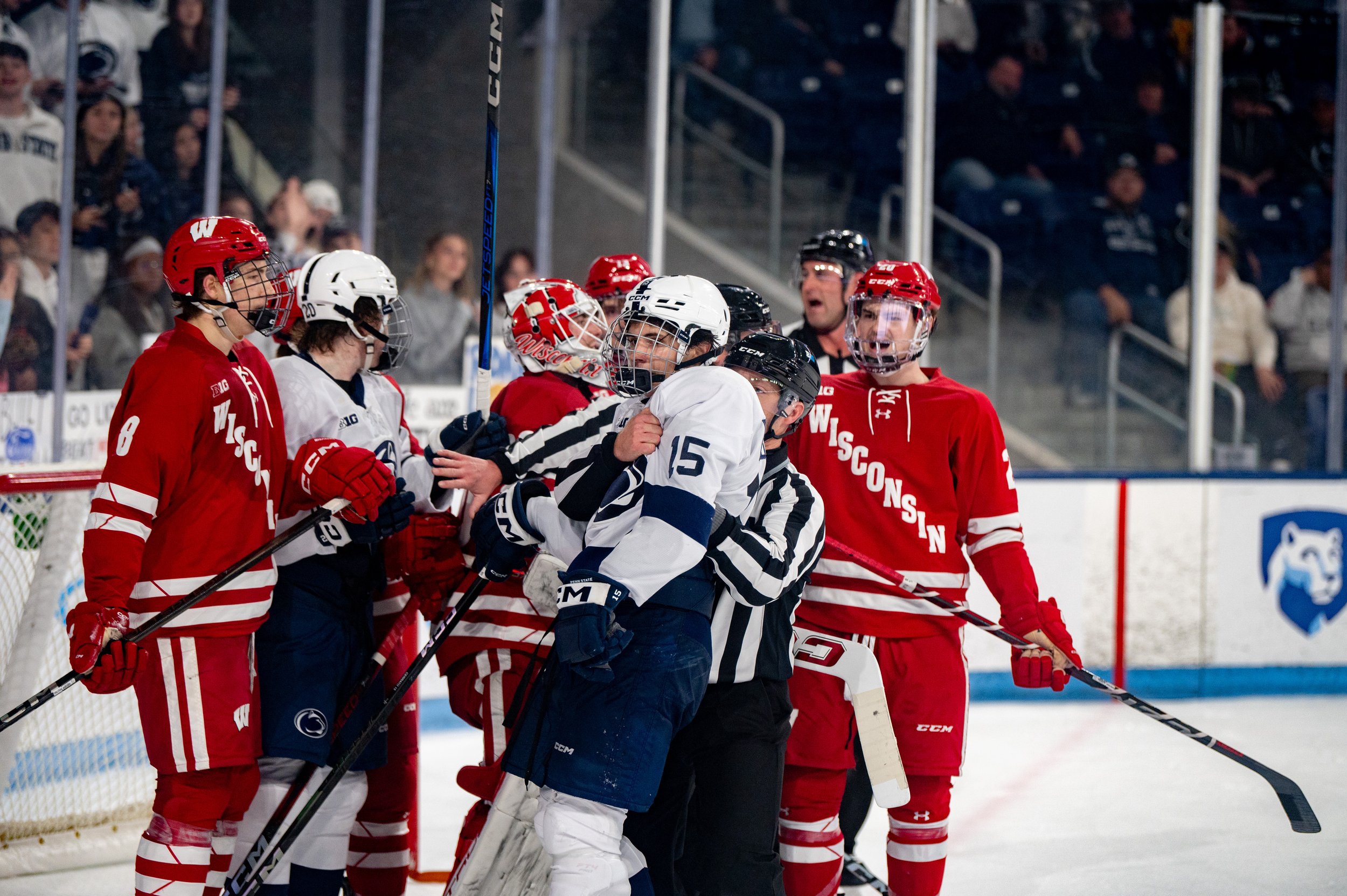 Penn State Forward Charlie Cerrato (15) is held back by an official after a brief skirmish with a Wisconsin player during the men's ice hockey game at Pegula Ice Arena on Saturday, Nov. 16, 2024 in University Park, Pa. The Badgers beat the Nittany Li