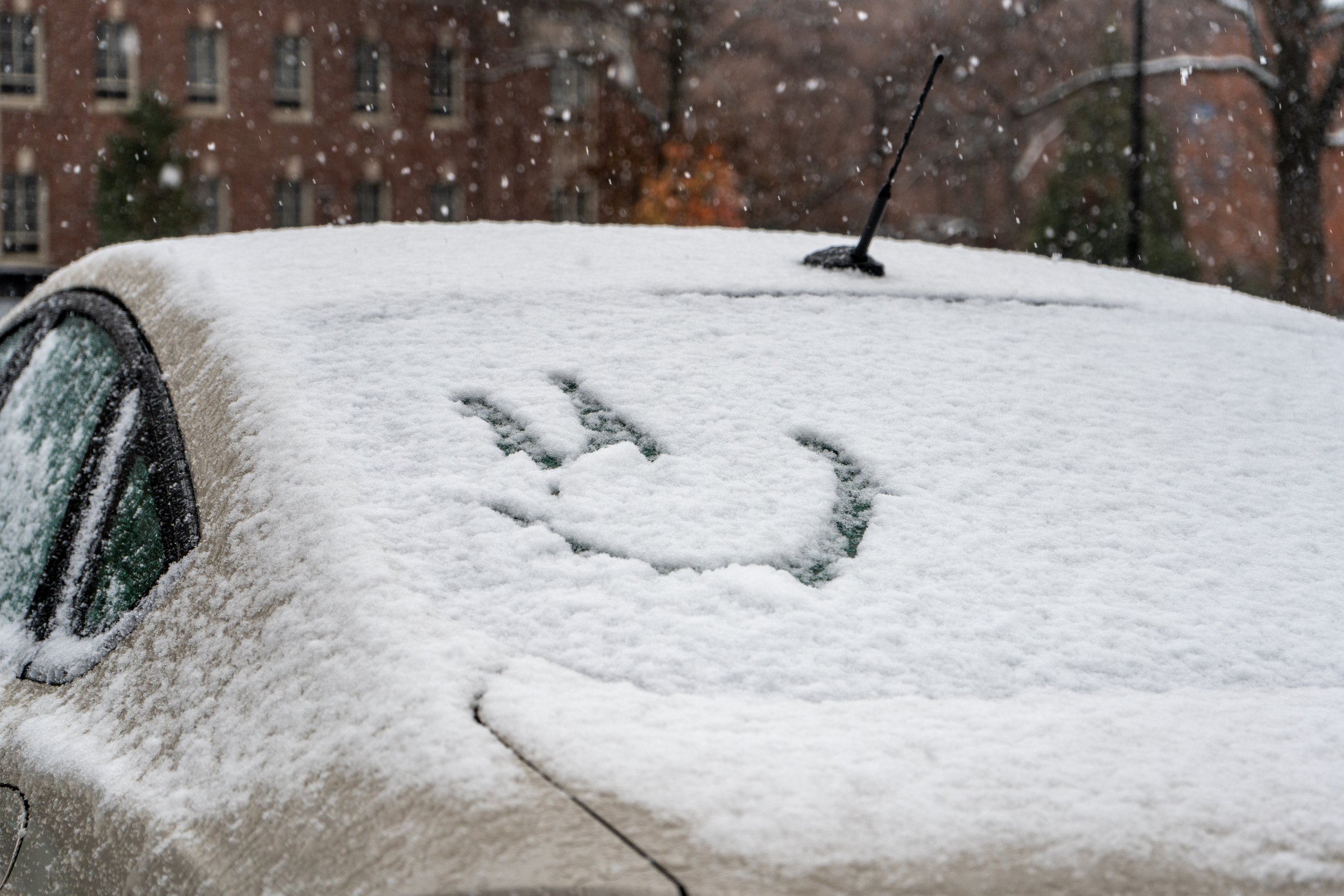 Snow falls on a parked car with a smiley face drawn into the back windshield on Friday, Nov. 22, 2024 in University Park, Pa.