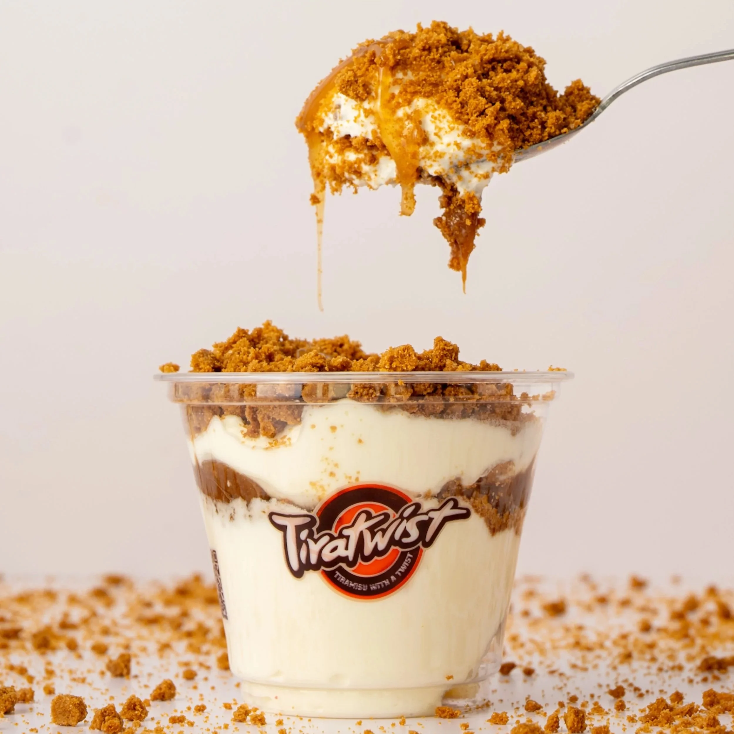 Layered dessert in a clear jar with vanilla pudding, crushed cookies, whipped cream, caramel sauce, and chopped nuts or cookie crumbs on top.