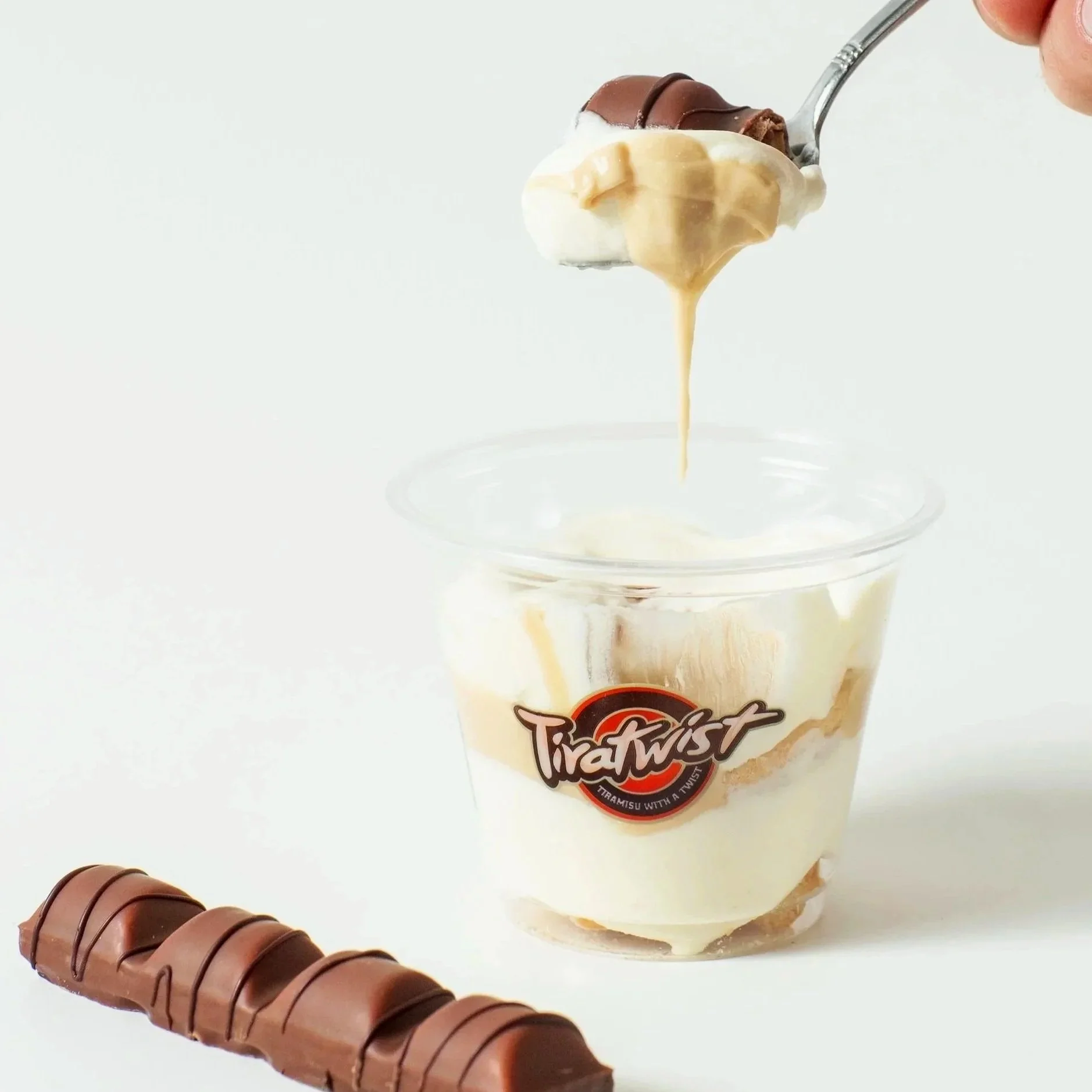 Dessert in a glass jar with whipped cream, chocolate syrup, and a chocolate-covered treat on top.
