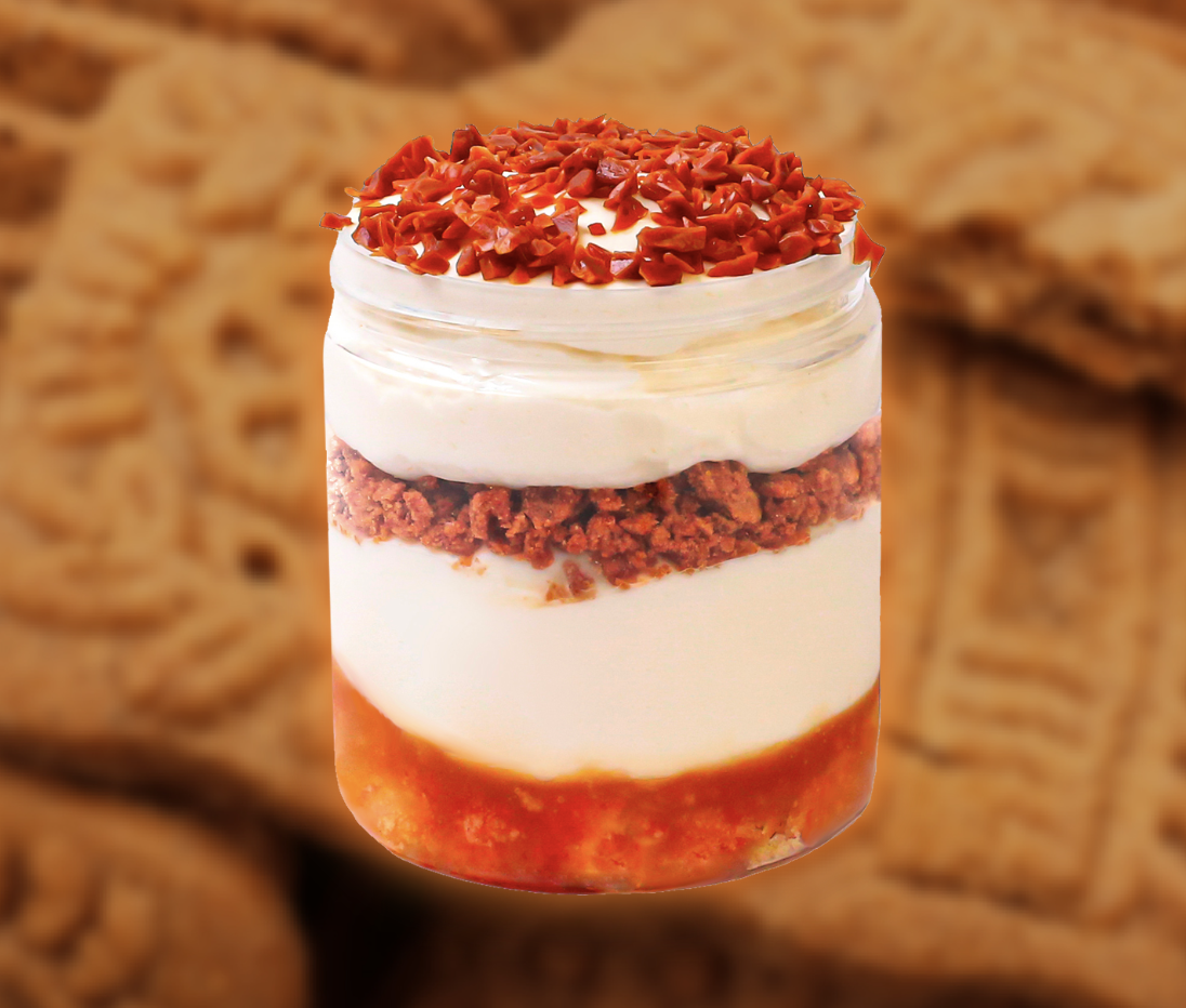 Layered dessert in a glass jar with crushed cookies, cream cheese or whipped topping, and chocolate shavings on top.