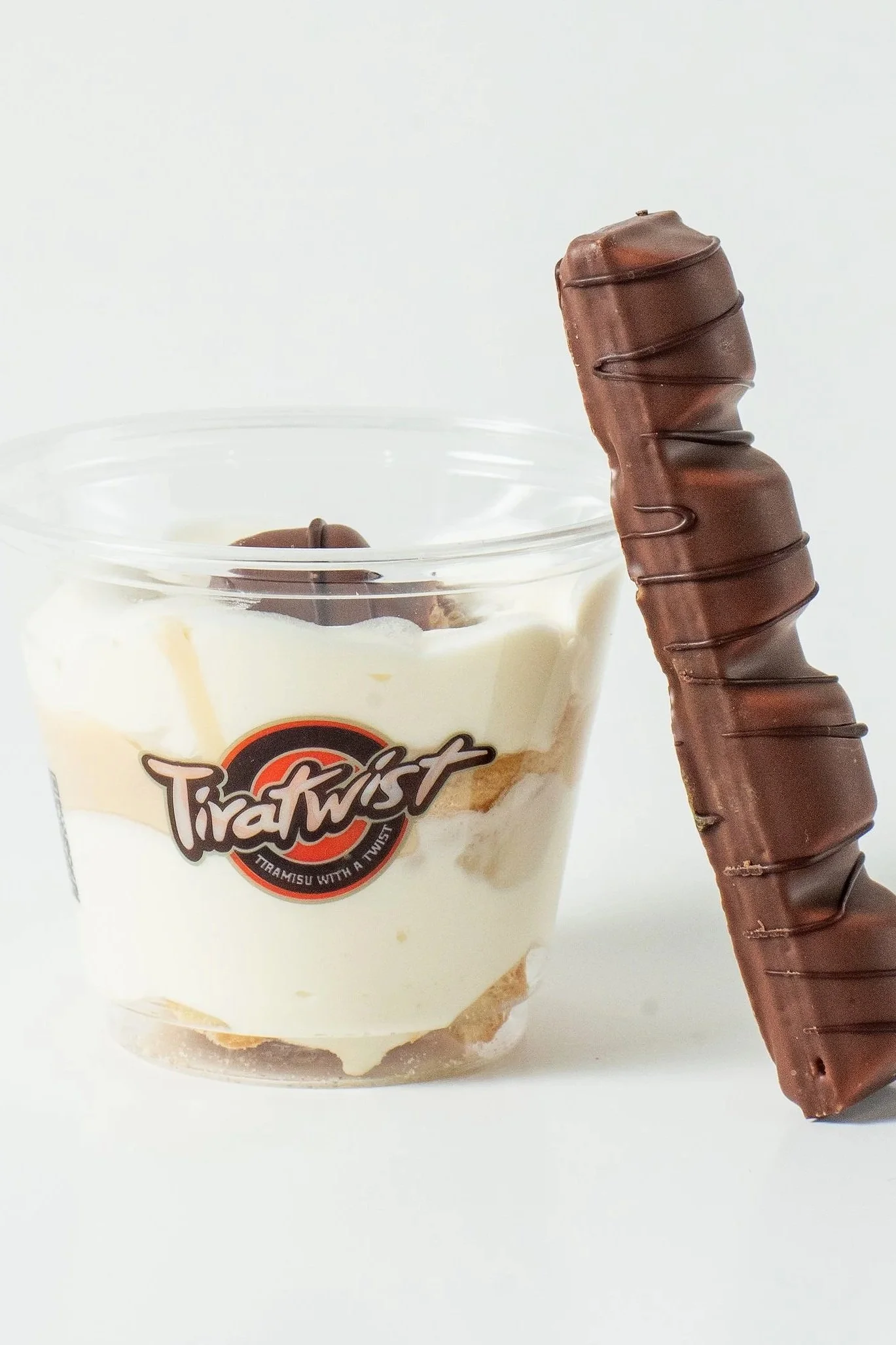 TiraTwist tiramisu cup topped with chocolate piece, and a chocolate wafer stick leaning against the cup.