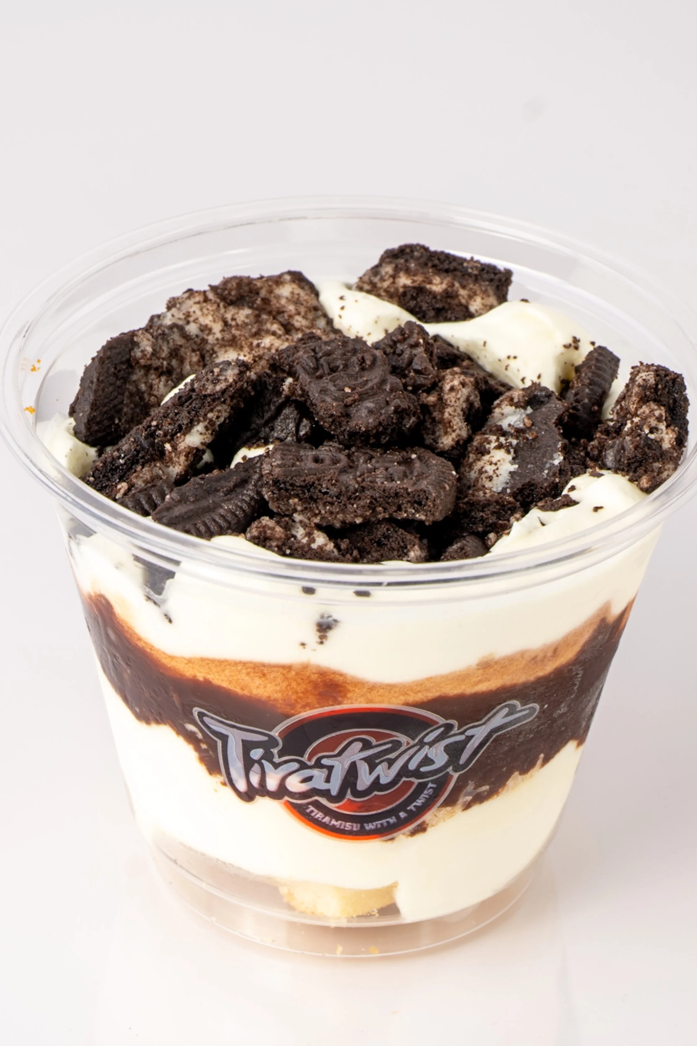Cookies and cream dessert with crushed cookies and cream topping in a clear plastic cup.
