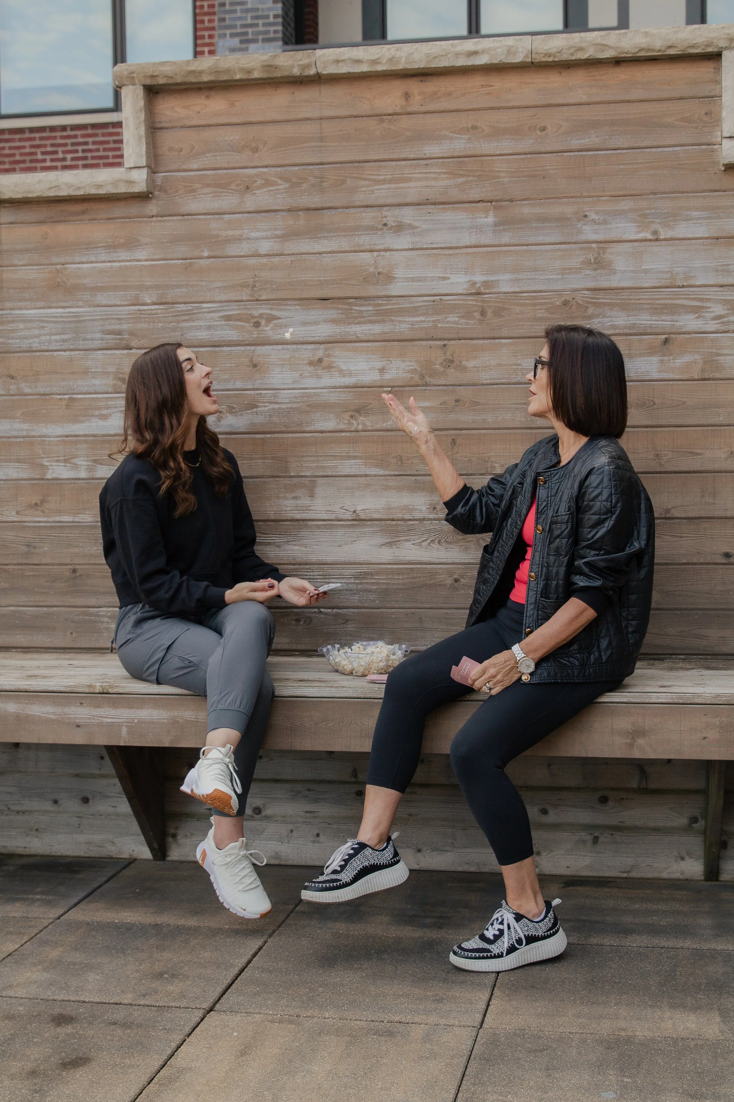Two women sharing a joyful moment outdoors, reflecting laughter, connection, and the choice to live with happiness and balance