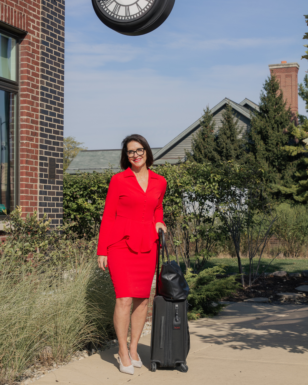 Woman in a red dress standing outdoors with luggage, symbolizing reflection, transition, and letting go of mental and emotional baggage
