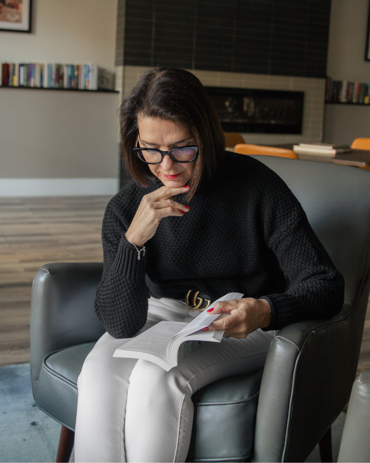 Kelly reading a book while seated in a cozy chair, reflecting during a quiet moment of prayer, faith, and spiritual growth.