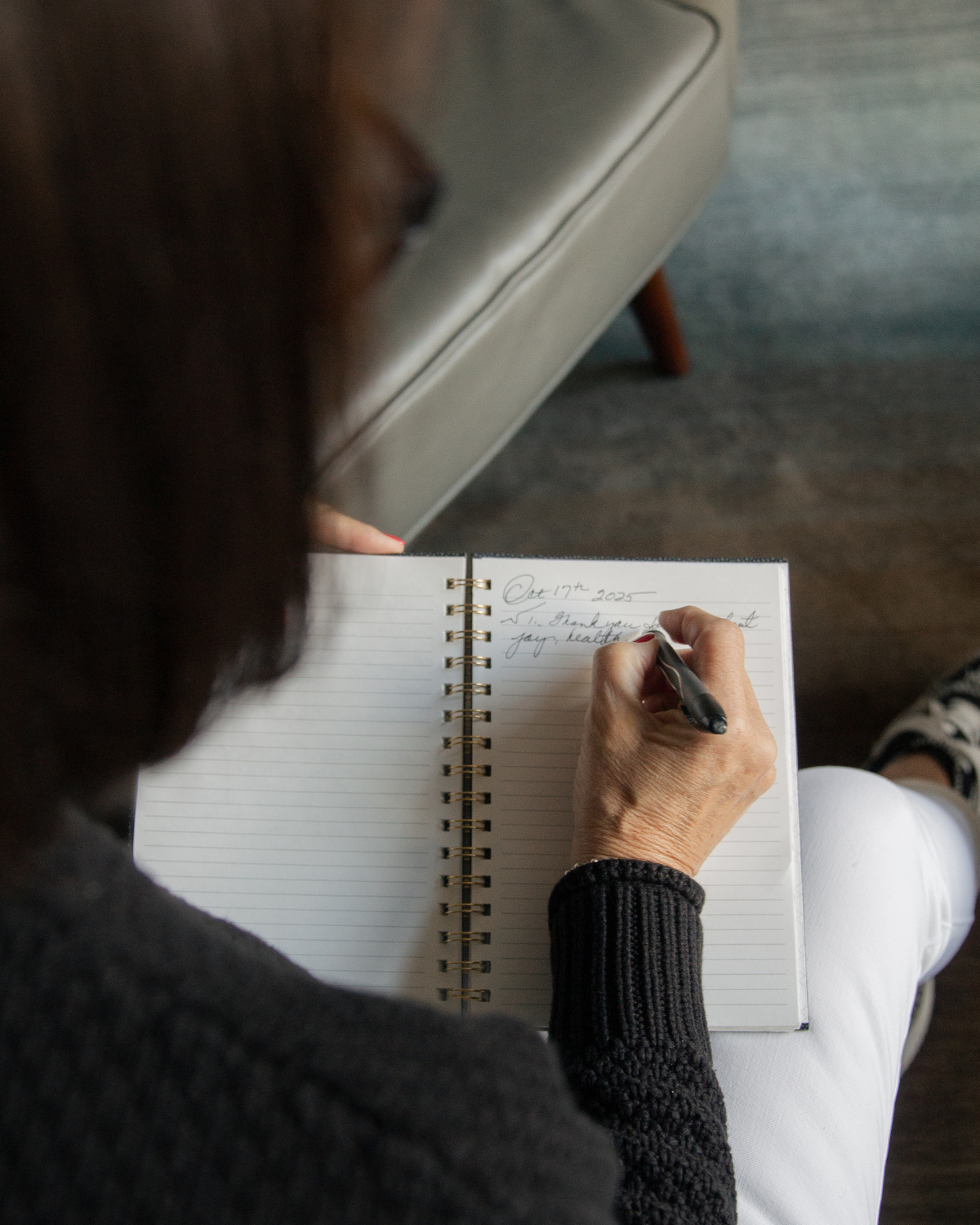 Overhead view of Kelly writing in a journal while seated indoors, reflecting on personal growth, gratitude, and finding meaning through intentional self-reflection.