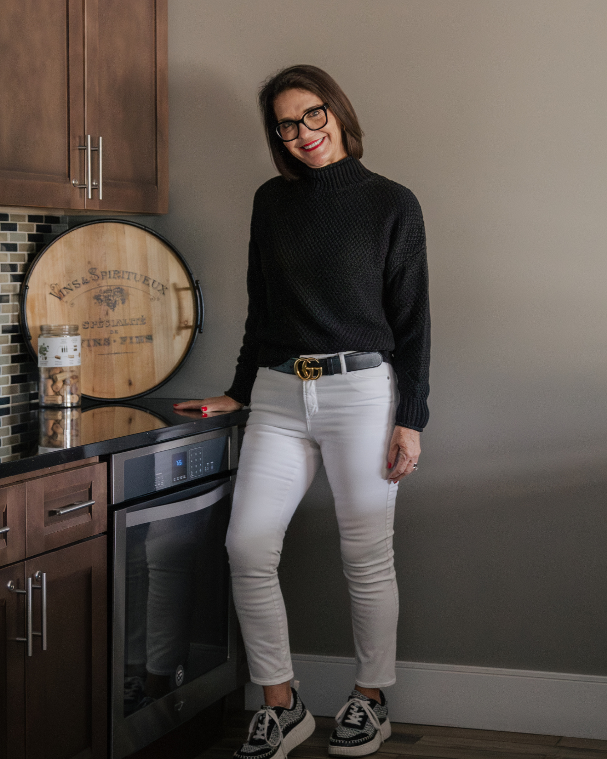 Kelly smiling in a kitchen while posing for a lifestyle portrait that reflects her warm, approachable approach to health, wellness, and intentional living.