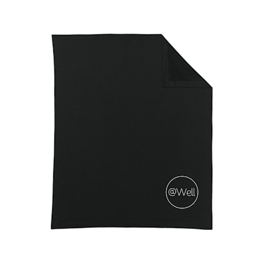 Black @Well Fleece blanket with white logo in the bottom right corner.