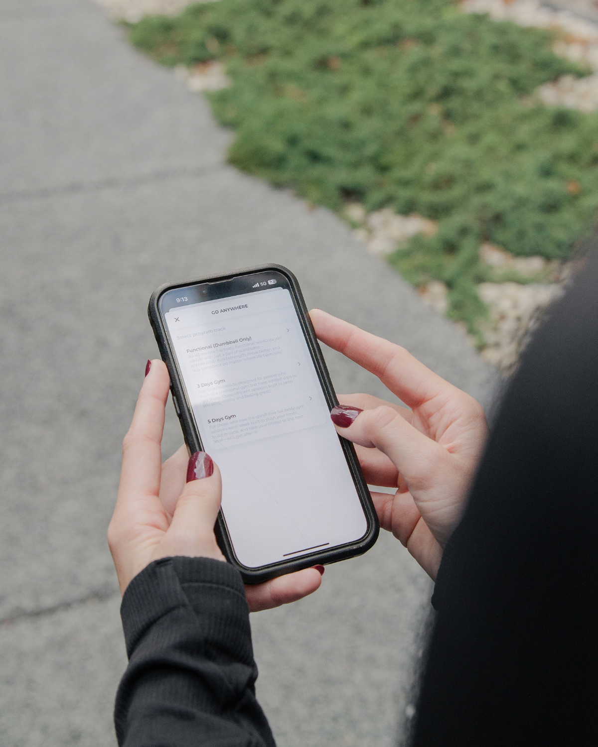 person checking fitness tracking data on phone while walking outdoors