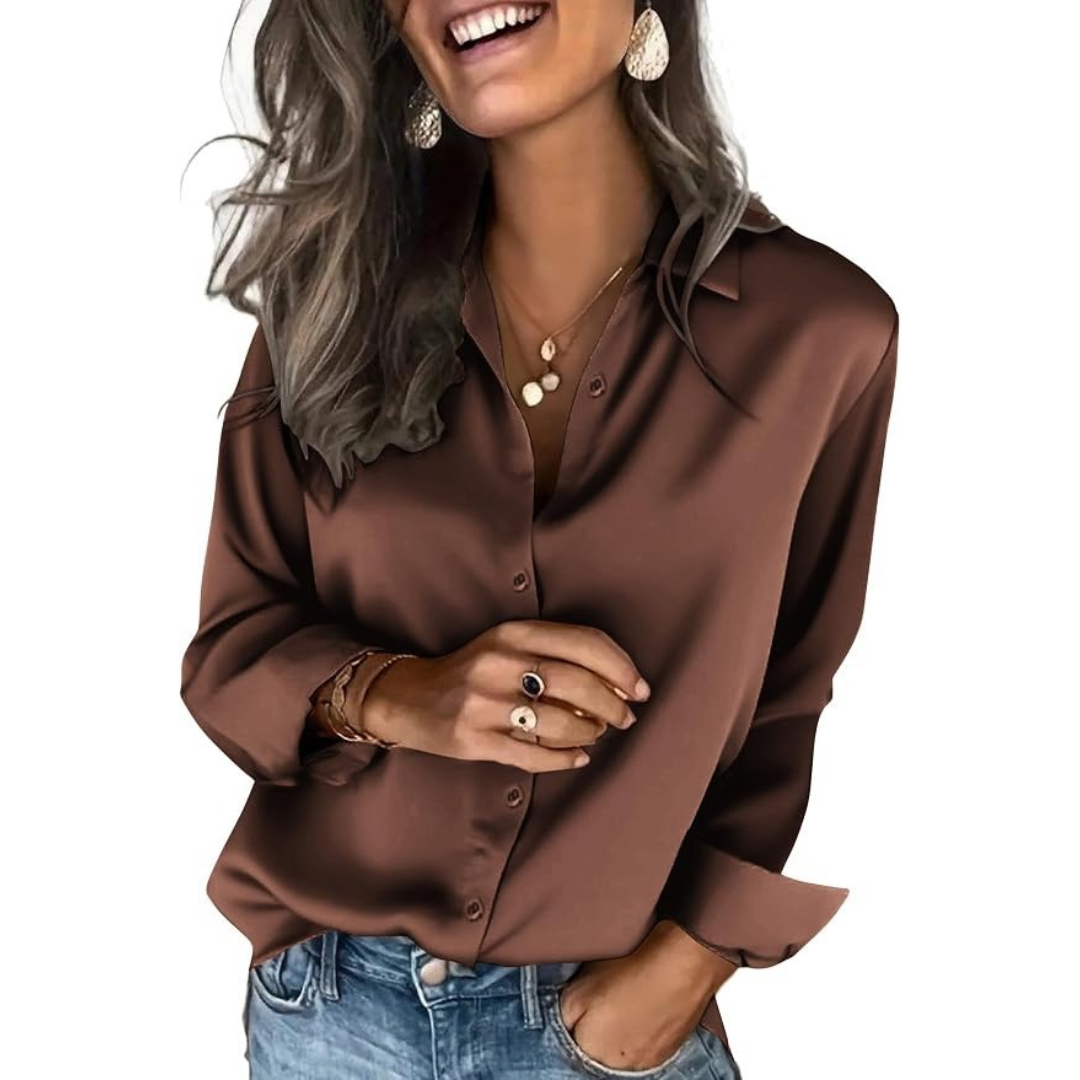 Woman wearing a chocolate-brown satin button-down blouse with a collar and long sleeves, styled with blue jeans and gold jewelry.