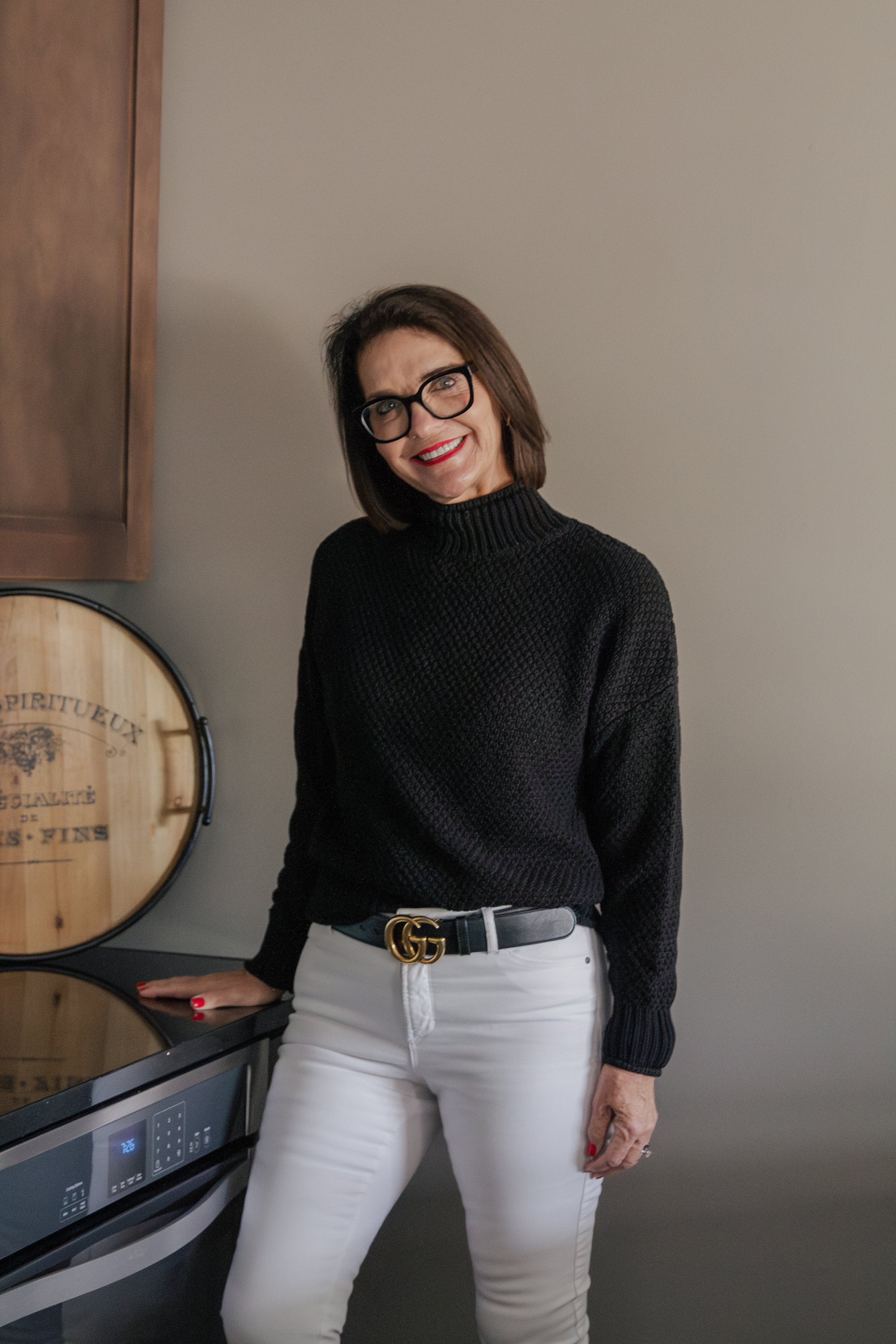 Kelly from @Well standing in a modern kitchen looking at the camera.