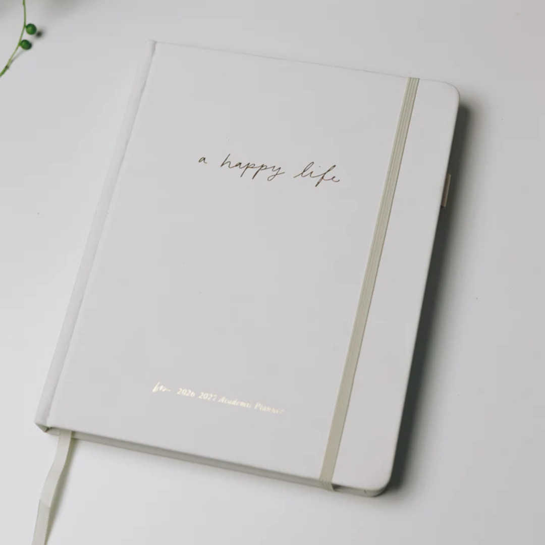 The Blessed Is She Happy Life 2026–2027 Mini Academic Planner with a white linen cover and elastic closure, designed to help women organize their schedules while growing in faith.