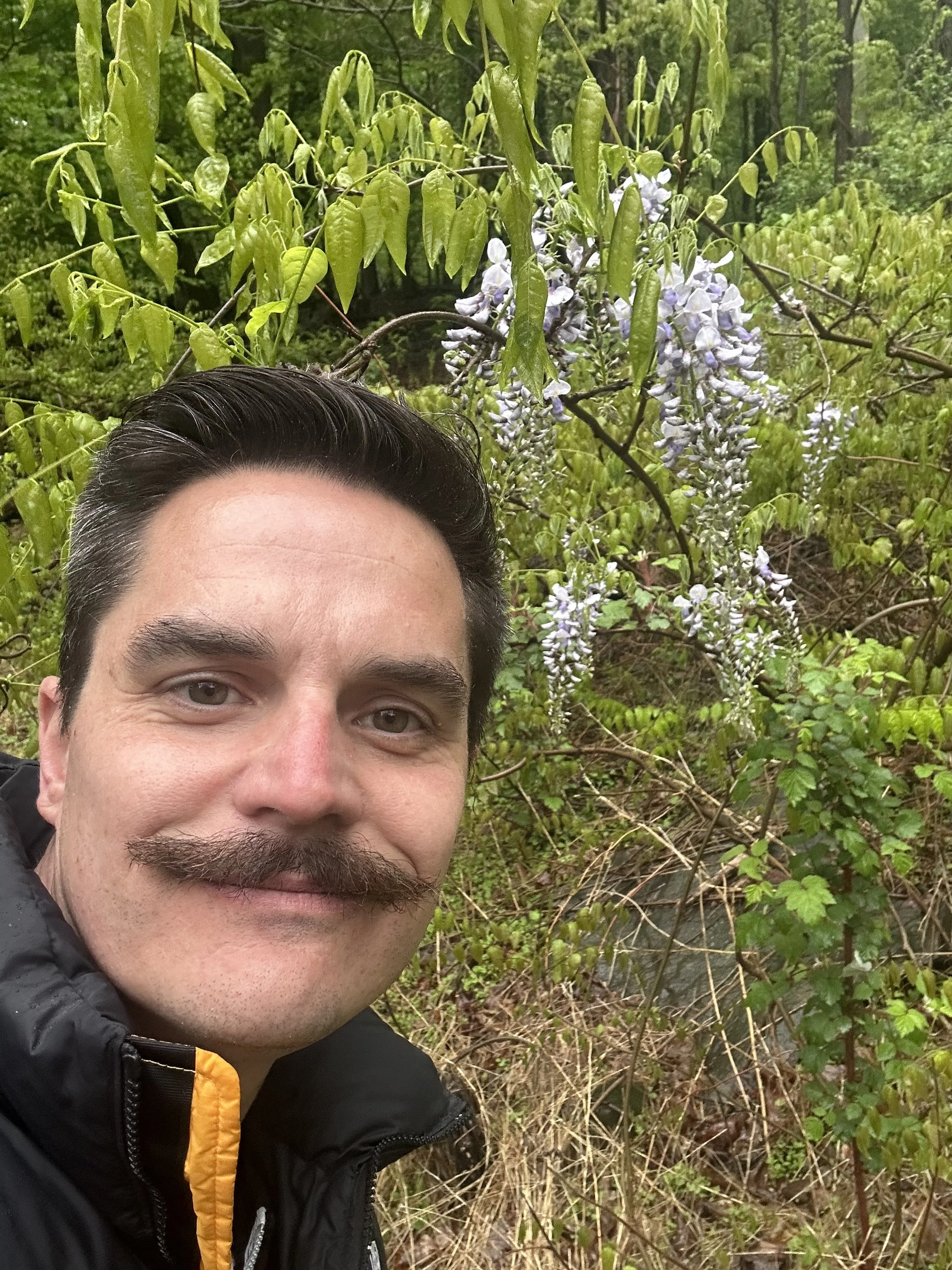 Man with long hair and mustache smiling at a market event.