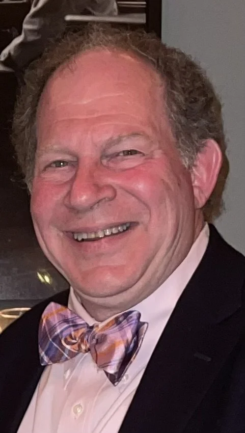 Man smiling, wearing a bow tie and suit